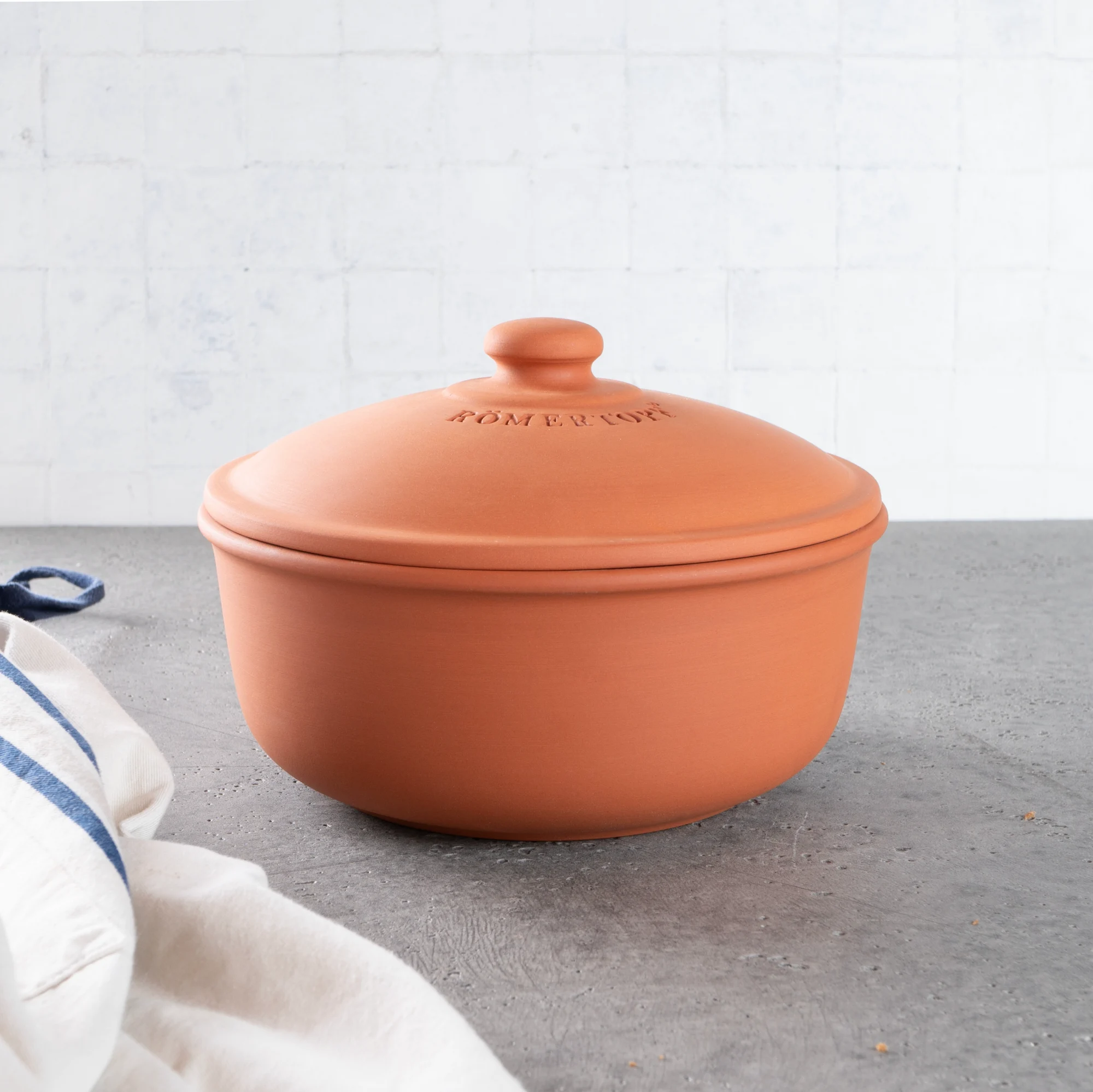 Römertopf Brotbacktopf aus Terracotta mit Deckel – Ideal für knuspriges Brot Terrakottafarbener Römertopf Brotbacktopf mit Deckel auf hellem Untergrund; der Topf hat eine ovale Form und eine glatte, matte Oberfläche.