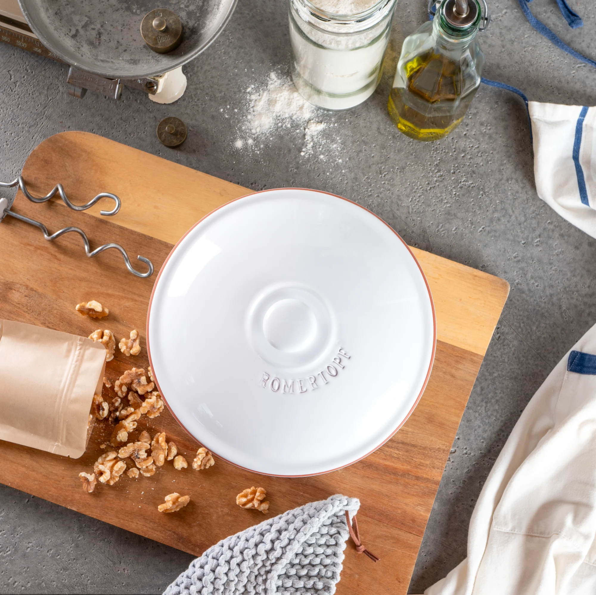 Römertopf Brotbacktopf oval weiß – Keramik-Backform zum Brotbacken Weißer Römertopf Brottopf mit Deckel aus Keramik, auf hellem Hintergrund stehend; geeignet zum Backen und Aufbewahren von Brot.