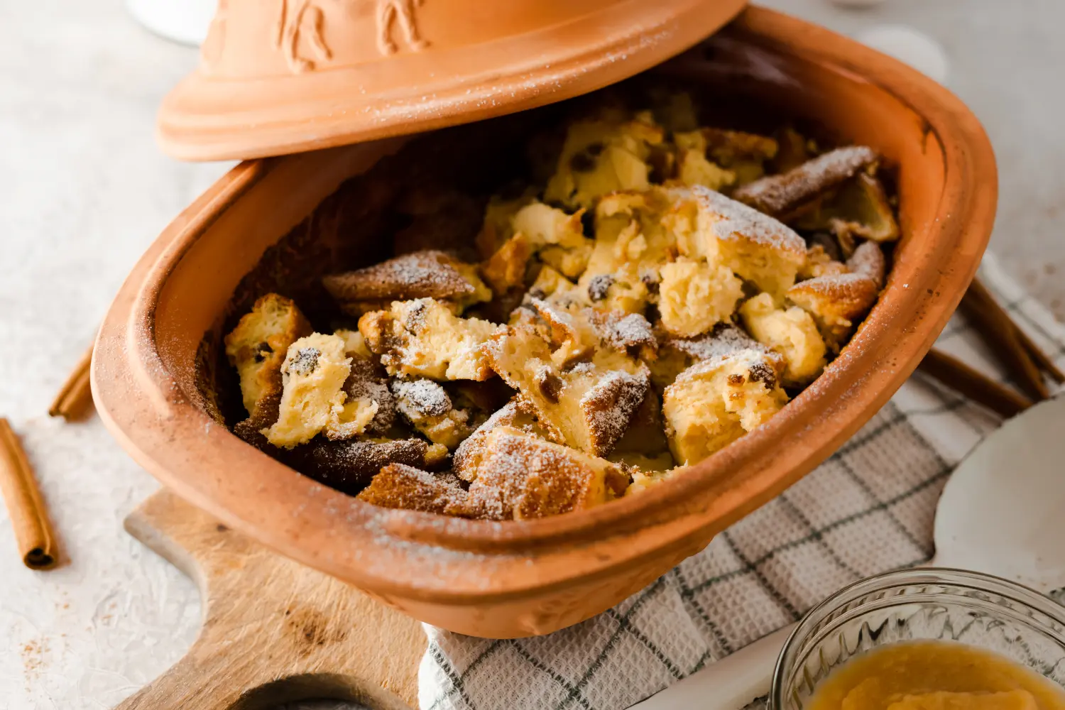 Saftiger Kaiserschmarrn mit Rosinen aus dem Römertopf – Einfaches Rezept Frisch zubereiteter Kaiserschmarrn aus dem Römertopf, goldbraun gebacken, angerichtet in einem tonfarbenen Bräter, bestreut mit Puderzucker und garniert mit roten Beeren.