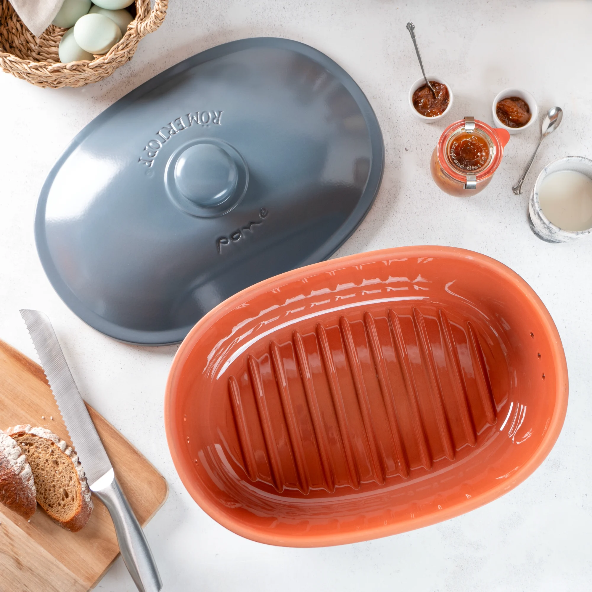 Römertopf Brottopf blaugrau mit Deckel – atmungsaktive Aufbewahrung für frisches Brot Römertopf Brottopf aus Keramik in Blaugrau mit passendem Deckel, ovaler Form und seitlichen Griffmulden, vorne mit eingeprägtem Schriftzug "RÖMERTOPF", auf hellem Hintergrund.