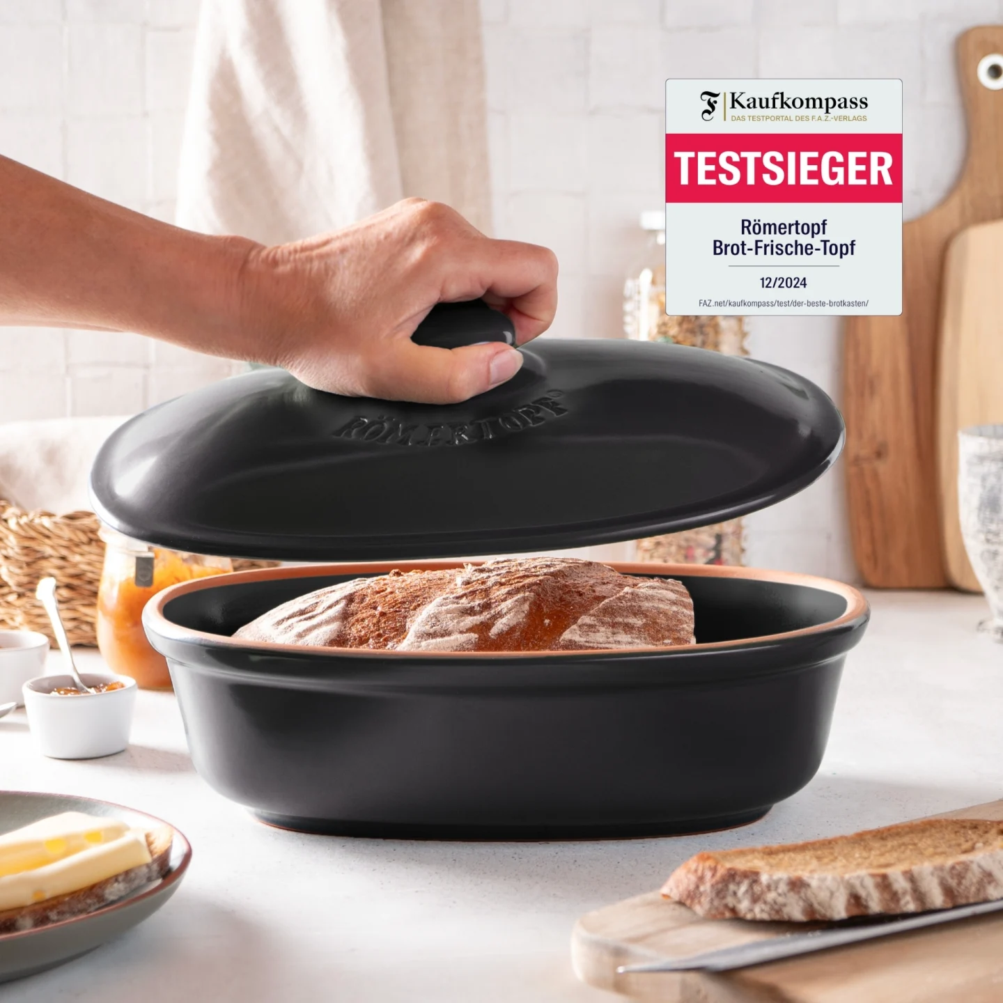 Römertopf Frische-Brottopf in Schwarz – Keramik Brottopf zur luftdichten Aufbewahrung von Brot Römertopf Frische-Brottopf in Schwarz mit Ton-Deckel, seitlicher Luftzirkulation und graviertem Brotsymbol, auf weißem Hintergrund.
