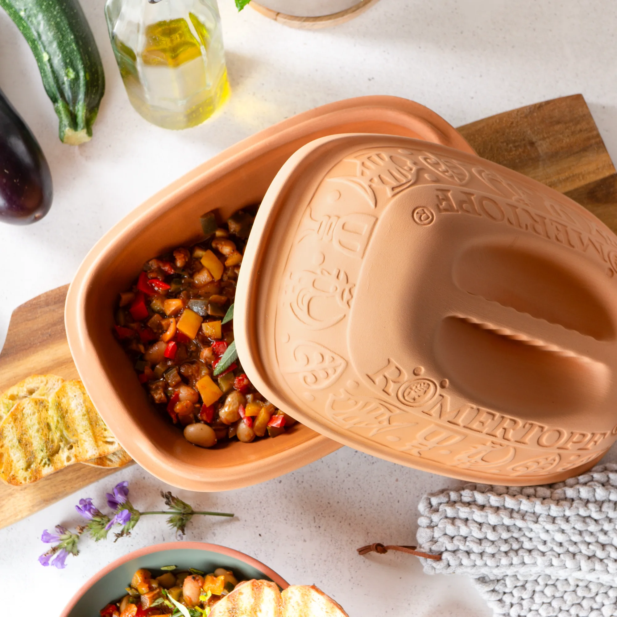 Römertopf Bräter klassisch für 2 Personen – Naturton Schmortopf mit Deckel Klassischer Römertopf-Bräter für 2 Personen aus naturfarbenem Ton mit verziertem Deckel, auf weißem Hintergrund.