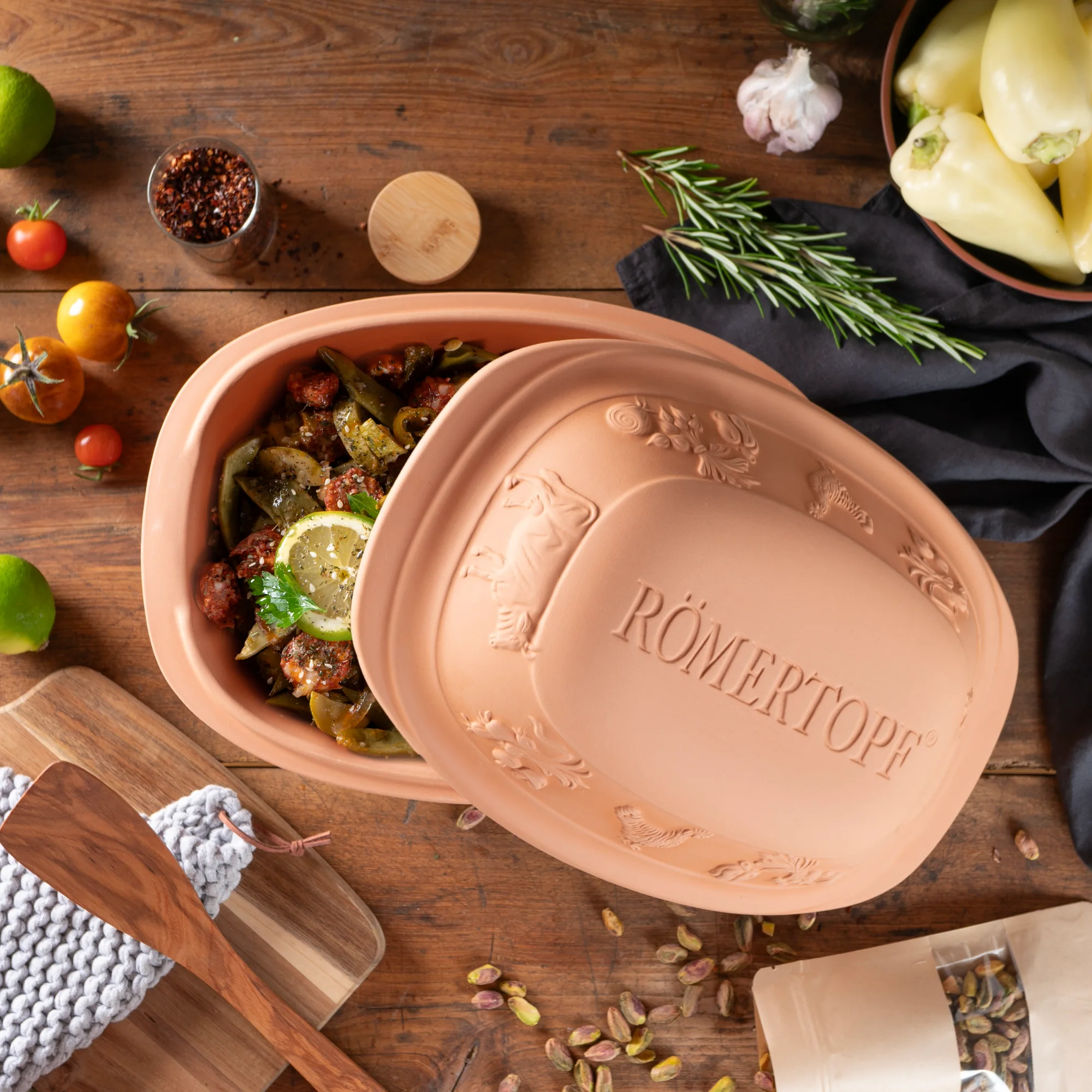 Römertopf Bräter Rustico aus Naturton mit Deckel – ovaler Tontopf zum fettarmen Garen Ovaler Römertopf-Bräter der Serie „Rustico“ aus naturbelassenem Ton mit Deckel, Vorderseite mit stilisiertem Hühnerrelief verziert, auf weißem Hintergrund.