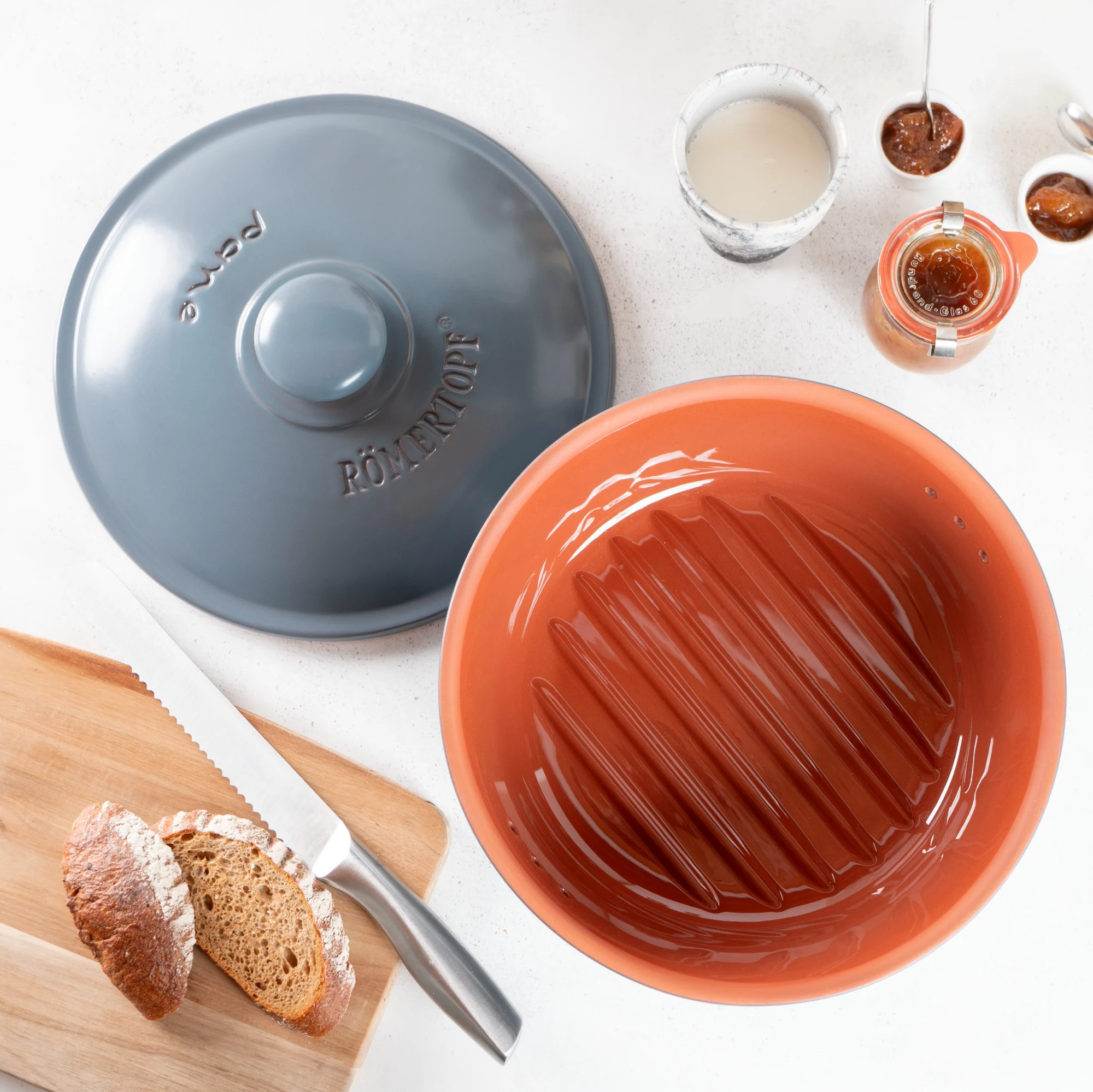 Römertopf Brottopf rund blaugrau aus Keramik mit Deckel – atmungsaktiver Frischetopf zur Brotlagerung Runder Römertopf Brottopf aus Keramik in Blaugrau mit passendem Deckel, seitlich belüftet durch kleine Luftlöcher, auf weißem Hintergrund.