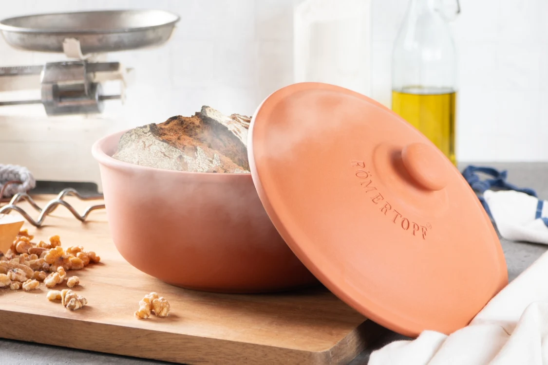 Drei braune Römertopf-Brotbackformen aus Ton in unterschiedlichen Größen stehen auf einem hellen Untergrund; die Formen sind rechteckig mit abgerundeten Ecken und haben keine Deckel.