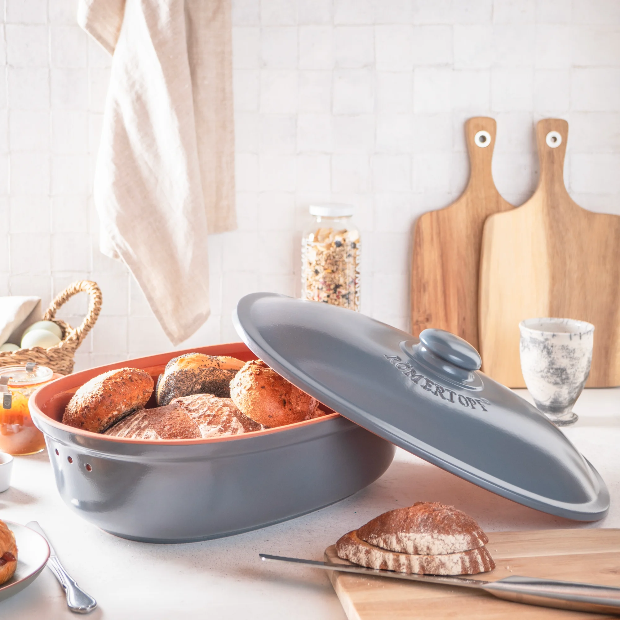 Römertopf Brottopf in Blaugrau aus Keramik mit Deckel – luftdicht & atmungsaktiv zur Brotaufbewahrung Römertopf Brottopf aus glasiertem Keramik in Blaugrau mit Deckel, ovaler Form und seitlichen Griffen, steht auf heller Oberfläche vor neutralem Hintergrund.