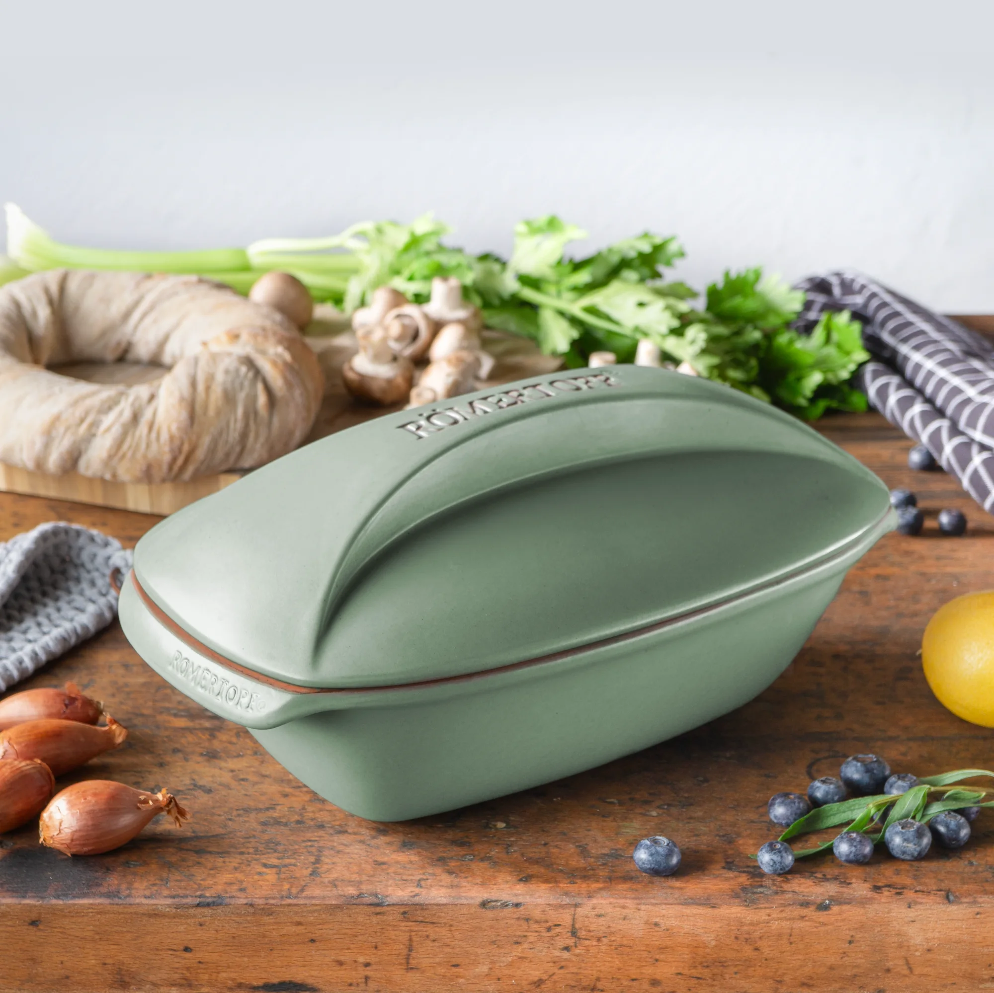 Römertopf Bräter Culinario in Grün – Keramik Kochgeschirr für schonendes Garen Grüner Römertopf Bräter der Serie Culinario mit Deckel, aus natürlichem Ton, auf weißem Hintergrund.