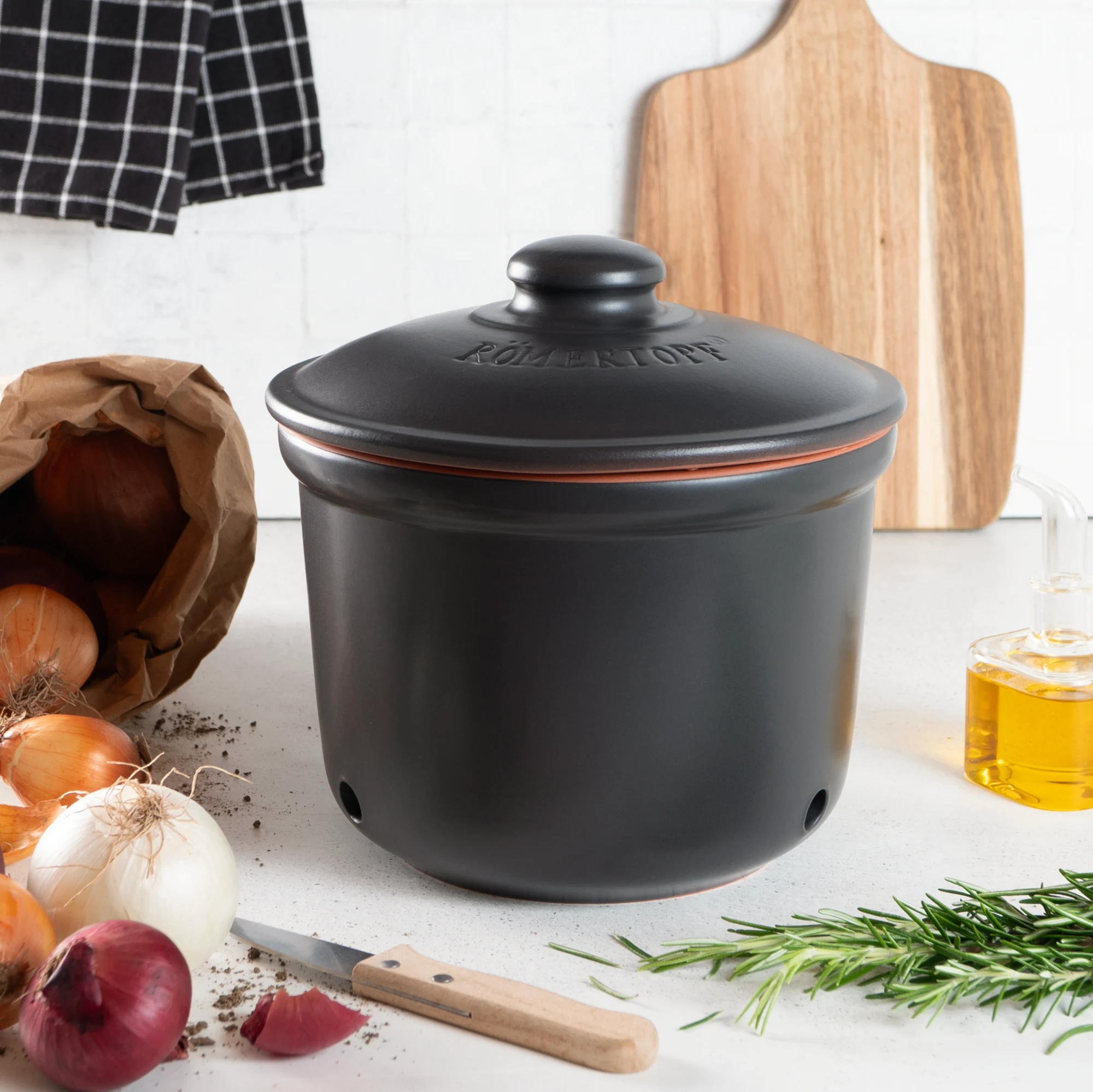 Römertopf Frischetopf Maxi Zwiebeltopf Schwarz – Atmungsaktive Keramik zur optimalen Lagerung von Zwiebeln Schwarzer Römertopf Frischetopf Maxi aus Keramik mit Deckel, gestaltet zur Aufbewahrung von Zwiebeln; der Topf zeigt seitliche Belüftungslöcher und trägt eine weiße Zwiebel-Illustration mit dem Schriftzug „Zwiebeln“.