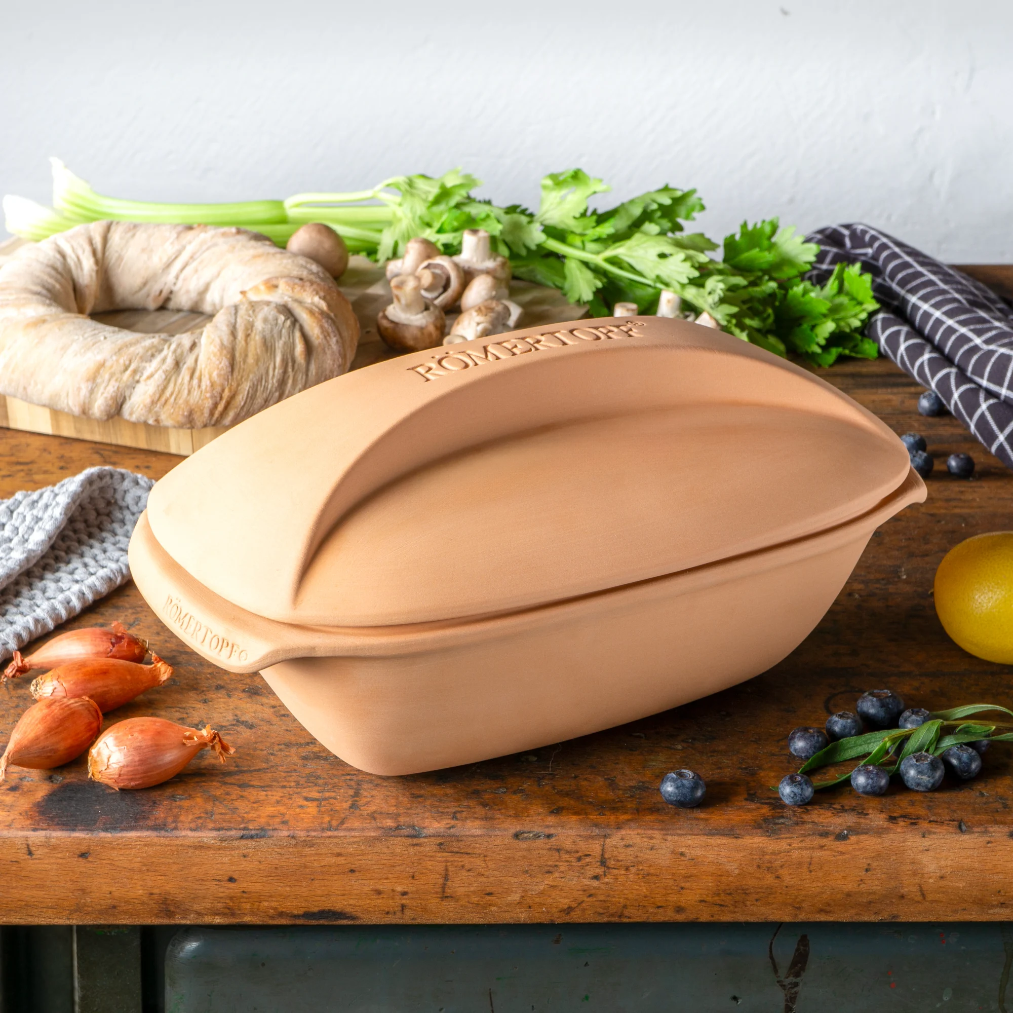Römertopf Bräter Culinario aus Terrakotta – traditioneller Tontopf zum gesunden Schmoren und Backen Terrakotta-Bräter mit Deckel der Marke Römertopf aus der Serie Culinario, oval geformt, glatte Oberfläche, naturfarben, stehend auf weißem Hintergrund.