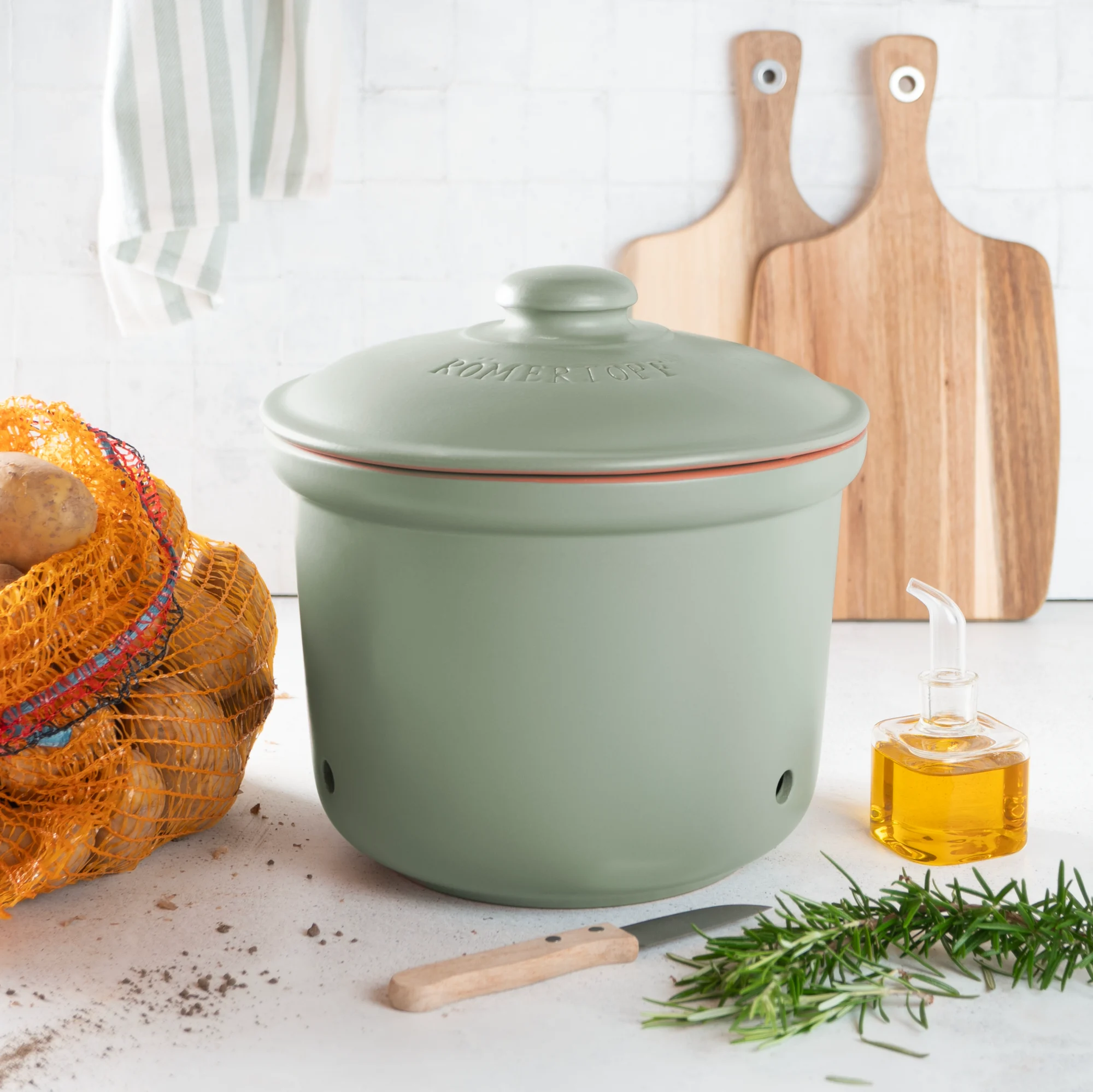 Römertopf Kartoffeltopf grün aus Keramik – Vorratstopf zur Aufbewahrung von Kartoffeln mit Belüftungssystem Grüner Römertopf-Kartoffeltopf mit Deckel, aus glasiertem Keramikmaterial, auf weißem Hintergrund – seitliche Ansicht mit sichtbarer Schriftprägung „Kartoffeltopf“ und dekorativen Belüftungslöchern.