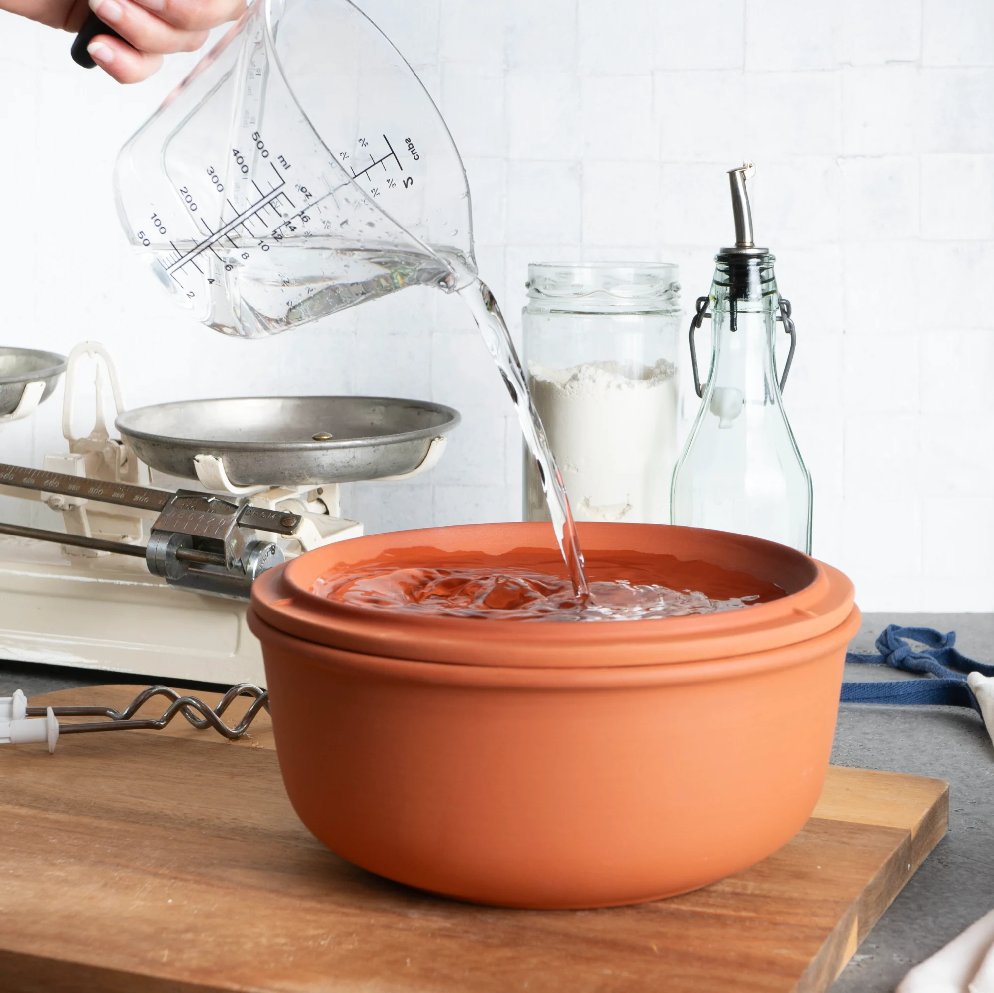 Römertopf Brottopf aus Terracotta – Brotbackform für knuspriges Brot Terrakottafarbener Römertopf Brotbacktopf mit Deckel, oval geformt, auf hellem Untergrund stehend.