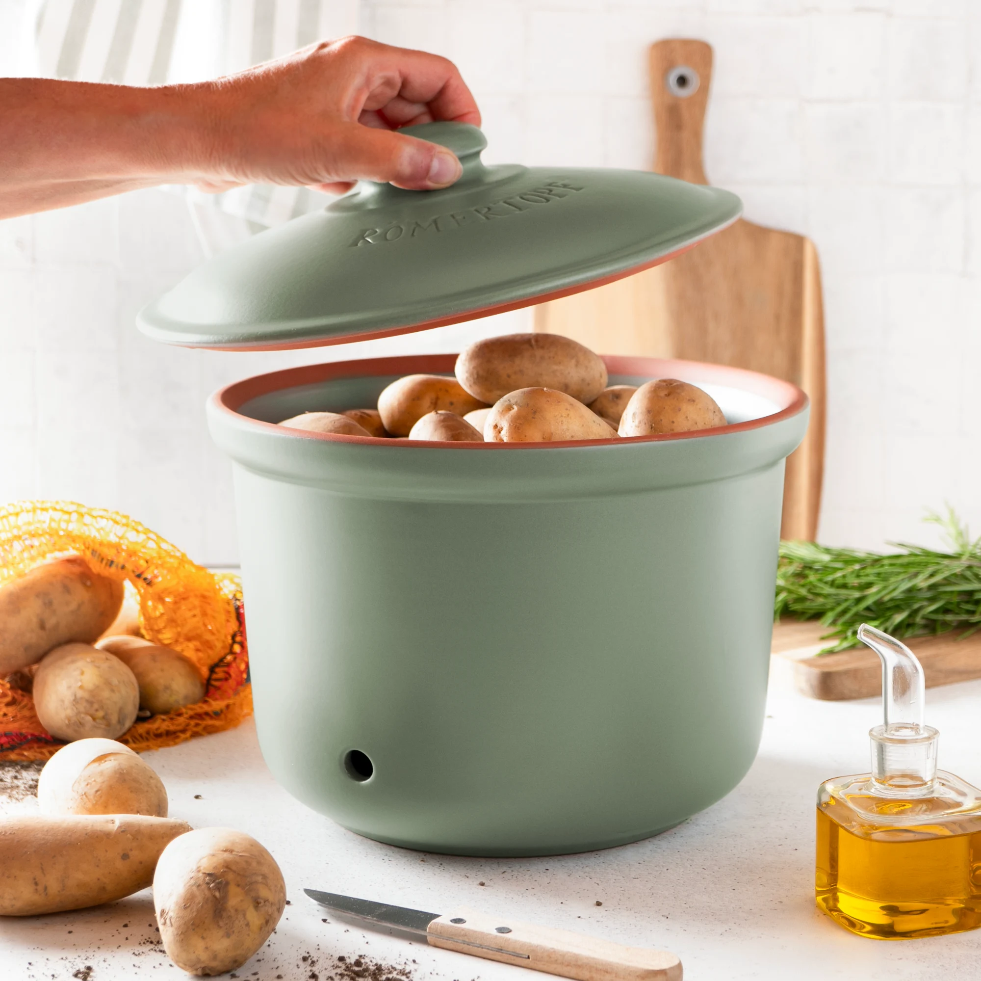 Römertopf Kartoffeltopf grün aus Keramik mit Deckel – atmungsaktiver Vorratsbehälter zur Lagerung von Kartoffeln Grüner Römertopf-Kartoffeltopf mit Deckel aus glasierter Keramik, auf einem weißen Hintergrund stehend.