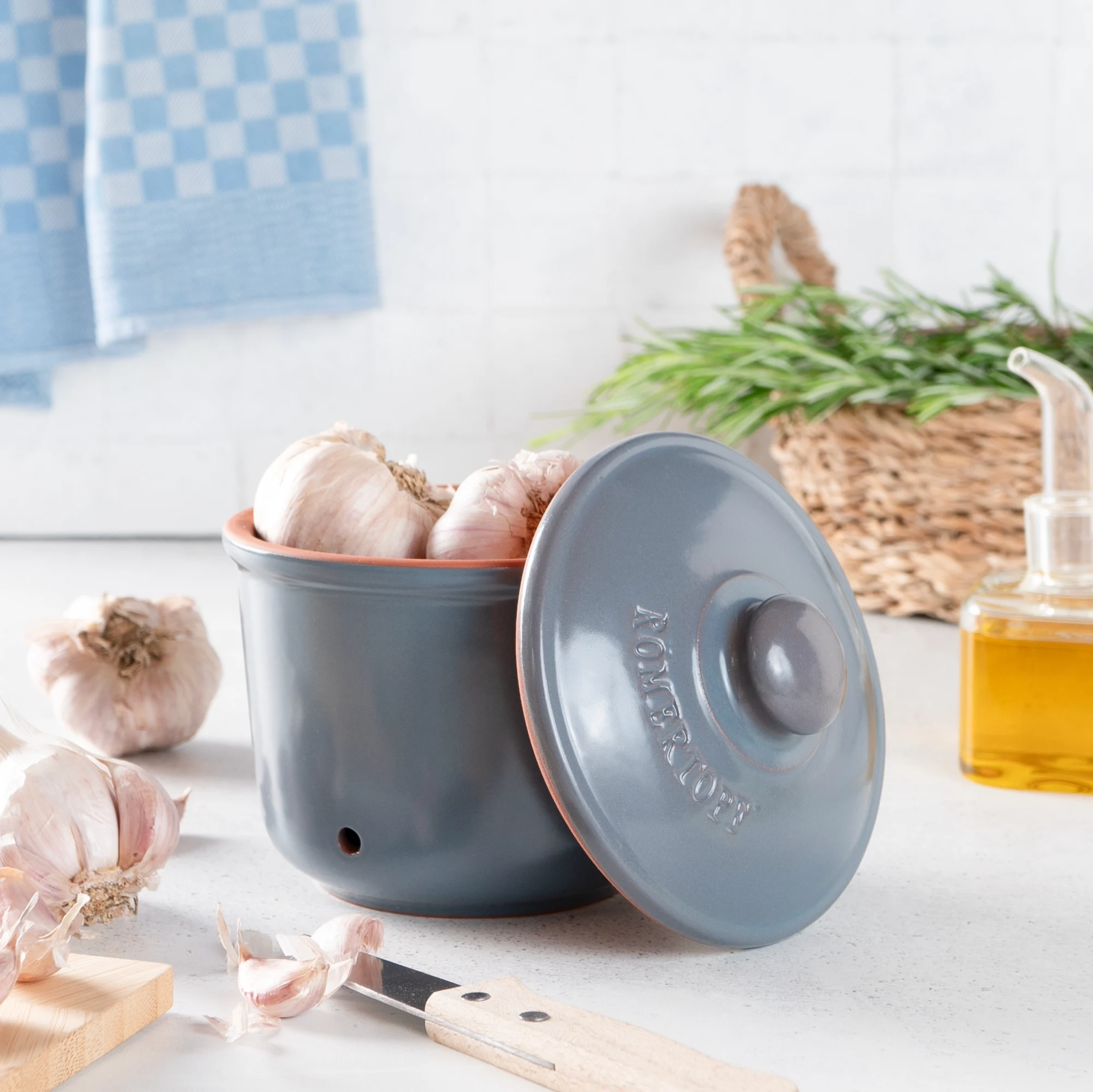 Römertopf Knoblauch-Frischetopf Mini in Blaugrau – Keramik Vorratsdose zur aromafrischen Aufbewahrung von Knoblauch Kleiner Römertopf-Frischetopf in Blaugrau mit Deckel, speziell für die Aufbewahrung von Knoblauch; steht auf einem hellen Untergrund, daneben liegen zwei Knoblauchknollen.
