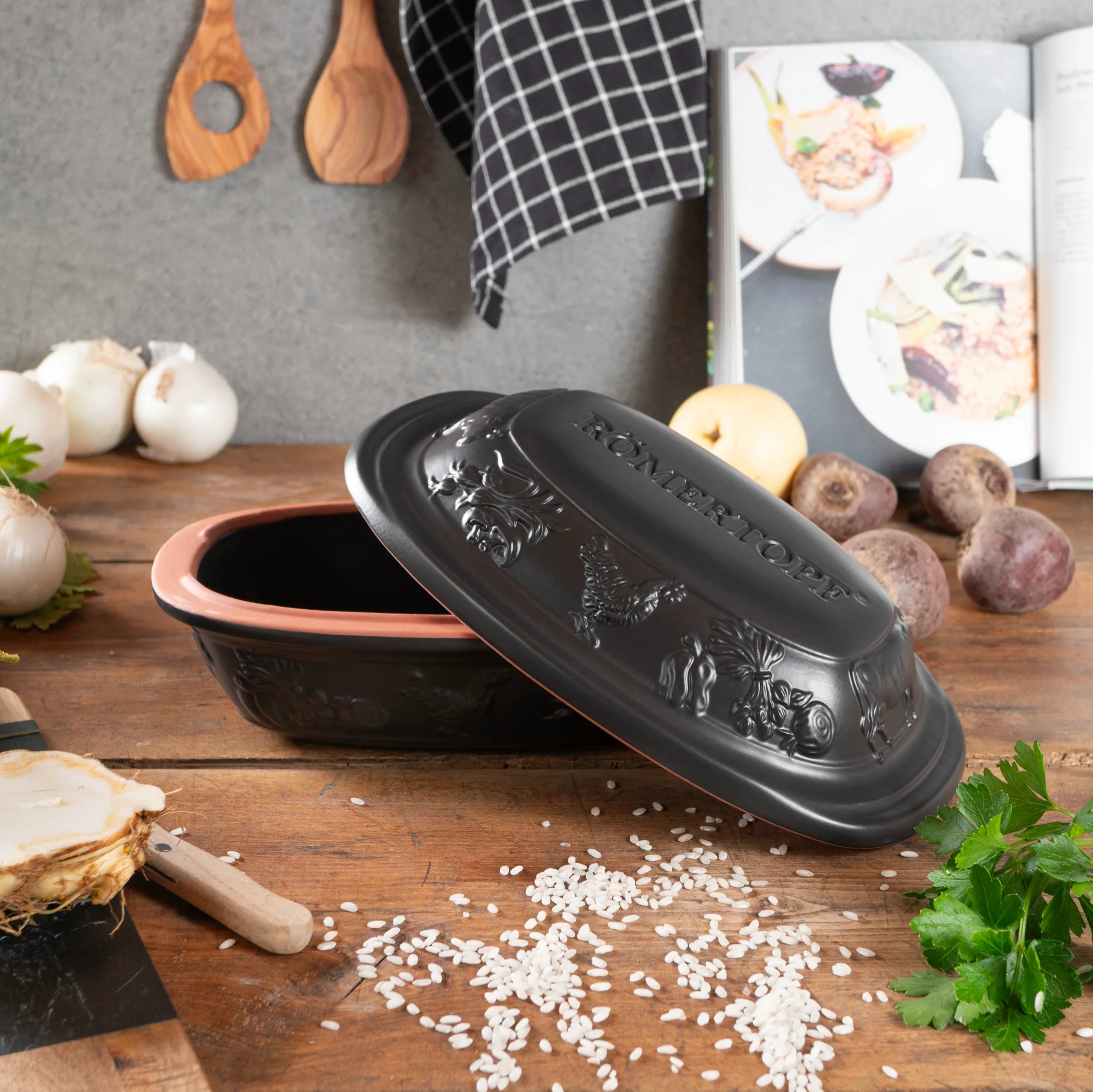 Römertopf Mini Bräter Schwarz – Keramik Bratentopf für kleine Portionen Schwarzer Römertopf Mini-Bräter aus Keramik mit Deckel, auf einem hellen Untergrund stehend; zeigt matte Oberfläche und kompaktes, ovales Design.