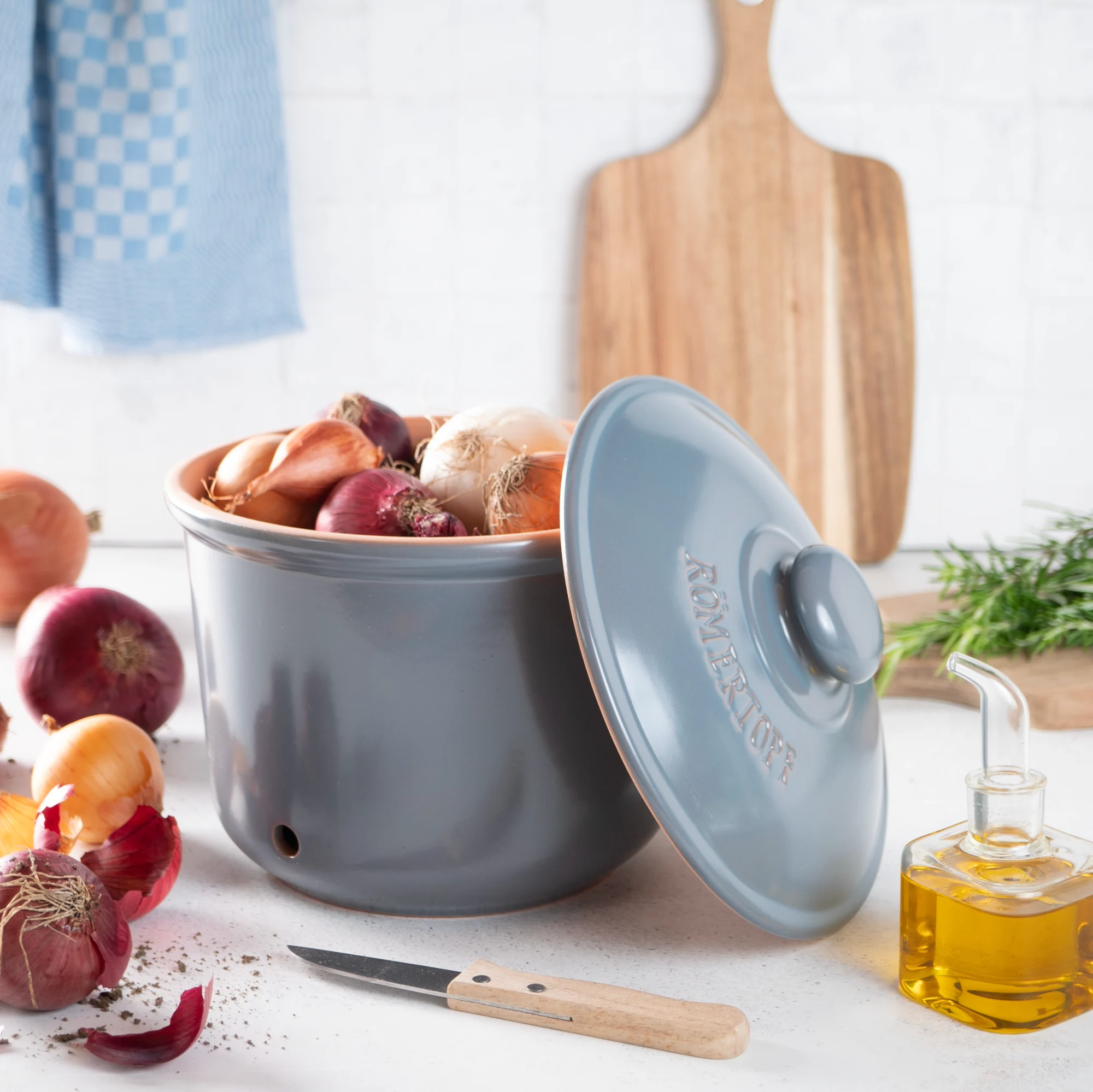 Römertopf Zwiebeltopf Maxi blaugrau – luftdurchlässiger Frischetopf zur Zwiebel-Aufbewahrung Blaugrauer Römertopf-Zwiebeltopf in MAXI-Größe mit Deckel, aus Keramik, stehend auf heller Oberfläche, mit seitlichen Lüftungslöchern und geschwungenem Schriftzug „Zwiebeln“ auf der Vorderseite.