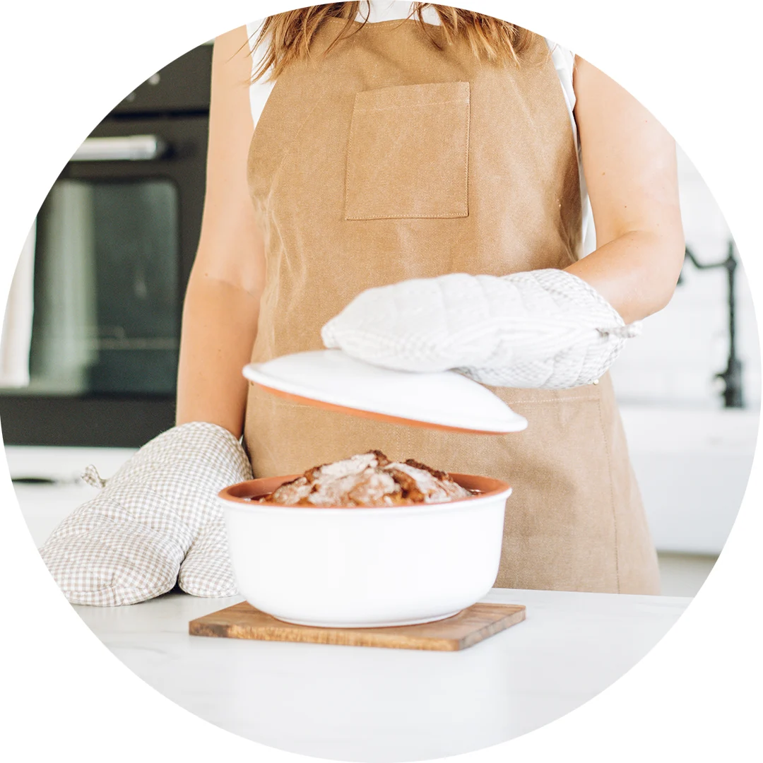 Römertopf Brotbacktopf aus Naturton zum Backen von knusprigem Brot Rechteckiger Römertopf aus Ton mit passendem Deckel, auf einem Holzbrett stehend; im Vordergrund liegt ein rundes, frisch gebackenes Brot mit knuspriger Kruste.