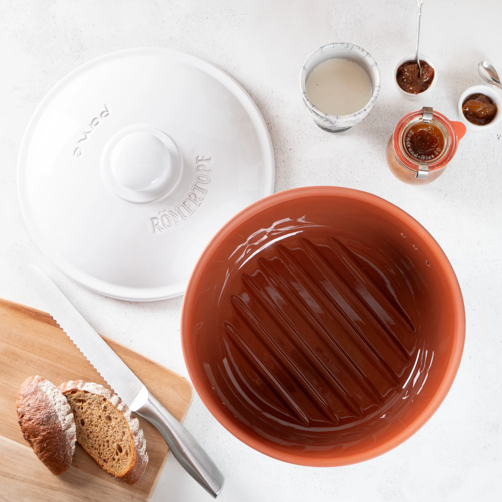 Römertopf Brottopf rund in Weiß – Keramik Frischetopf zur Brotaufbewahrung Runder, weißer Römertopf Brottopf mit Deckel aus Keramik zur Aufbewahrung von Brot; im Hintergrund neutraler Untergrund.