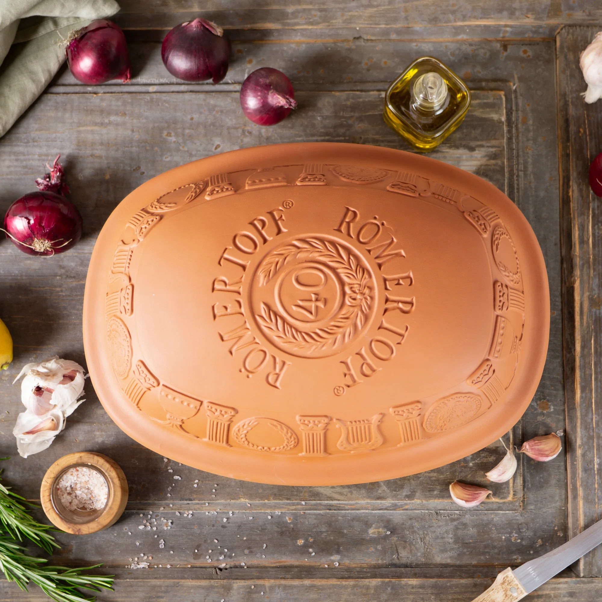 Römertopf Jubiläums-Bräter 40 Jahre – Klassischer Tontopf für gesundes Kochen Rechteckiger Römertopf-Bräter aus naturfarbenem Ton mit Deckel, seitlichen Griffmulden und Jubiläumsprägung „40 Jahre“ auf dem Deckel, vor weißem Hintergrund.
