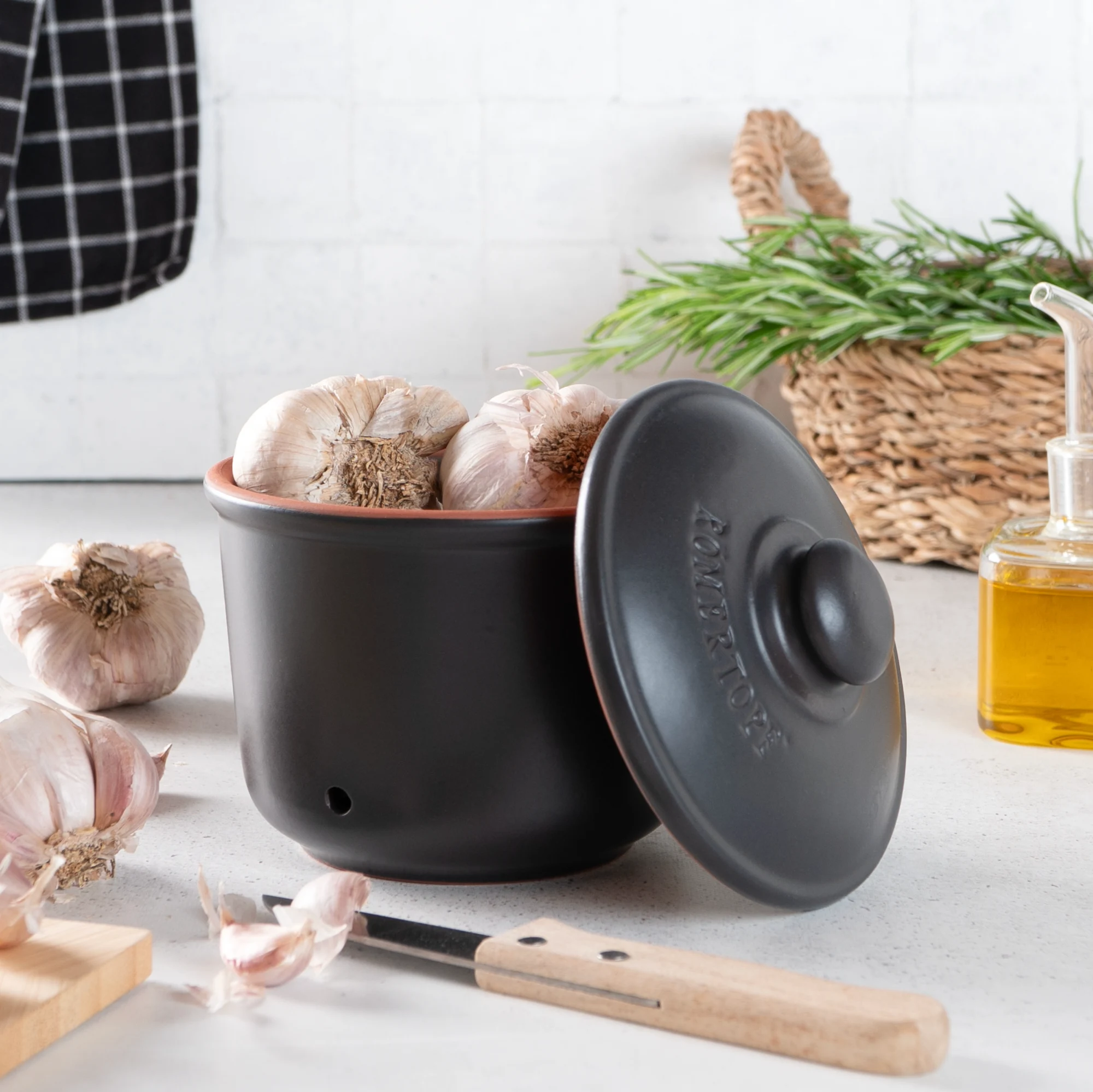 Römertopf Knoblauch-Frischetopf Mini Schwarz – luftdichter Keramikbehälter zur Aufbewahrung von Knoblauch Kleiner, schwarzer Römertopf-Frischetopf für Knoblauch mit seitlichen Belüftungslöchern und Deckel, auf weißem Hintergrund.