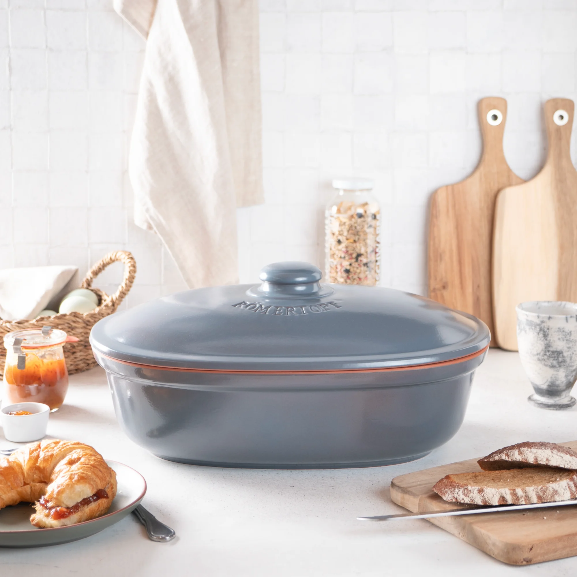 Römertopf Brottopf blaugrau mit Deckel – atmungsaktive Aufbewahrung für frisches Brot Römertopf Brottopf in Blaugrau aus Keramik mit Deckel, in ovaler Form, auf heller Oberfläche stehend – zur luftdurchlässigen und hygienischen Aufbewahrung von Brot.