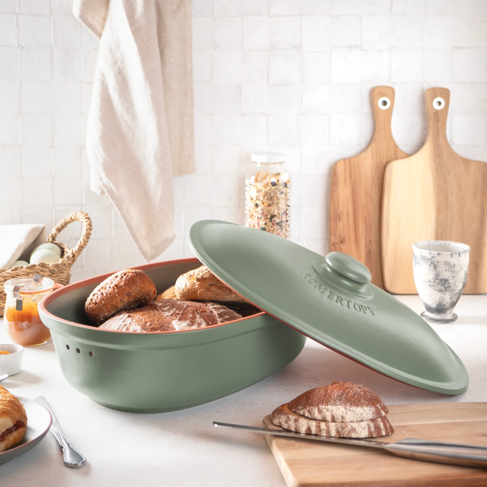 ROEMERTOPF Brottopf Maxi Grün – Brotbox für lange Frische aus Naturton Grüner Römertopf Brottopf Maxi mit Deckel, aus Keramik, auf dunklem Untergrund stehend; seitliche Schrift "Römertopf" erkennbar, moderne ovale Form zur Aufbewahrung von Brot.