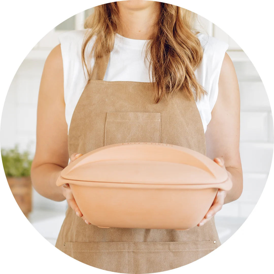 Römertopf Bräter aus Naturton mit Deckel – Klassiker zum fettarmen Garen Ovaler Römertopf-Bräter aus naturfarbenem Ton mit Deckel, auf einem hellen Untergrund platziert.