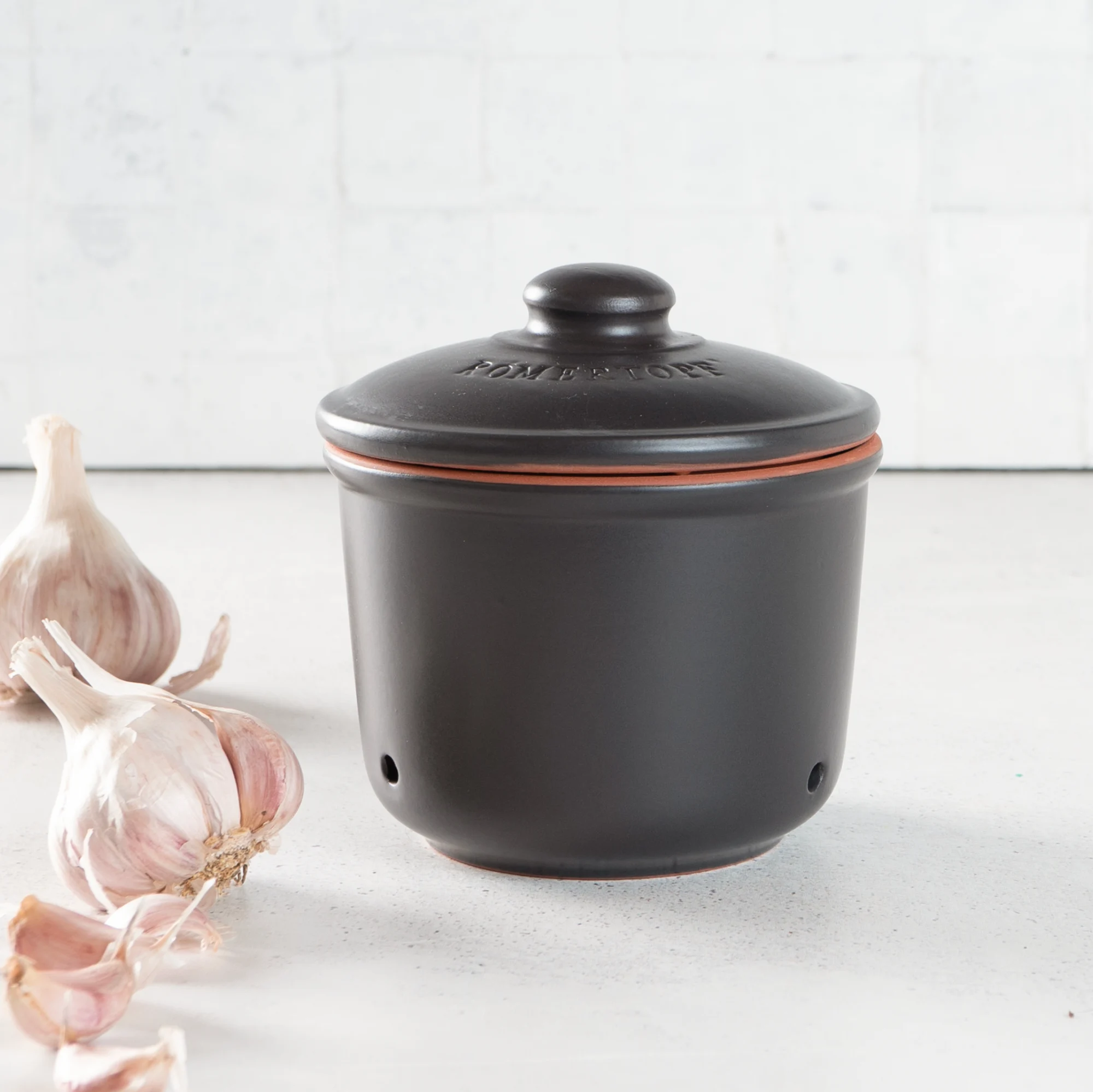 Römertopf Knoblauch-Frischetopf Mini in Schwarz – luftdichter Keramikbehälter zur optimalen Lagerung von Knoblauch Schwarzer Römertopf Knoblauch-Frischetopf Mini mit Deckel, aus Keramik, auf weißem Hintergrund; Deckel mit kleinen Belüftungslöchern und „Knoblauch“-Prägung.