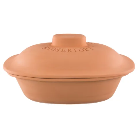 Römertopf Bräter Trend aus Ton – traditionelles Schmorgefäß für aromatische Ofengerichte Römertopf Bräter aus naturbelassenem Ton mit Deckel, in ovaler Form, auf einem hellen Untergrund stehend – traditionelles Kochgeschirr für fettfreies Garen im Ofen.