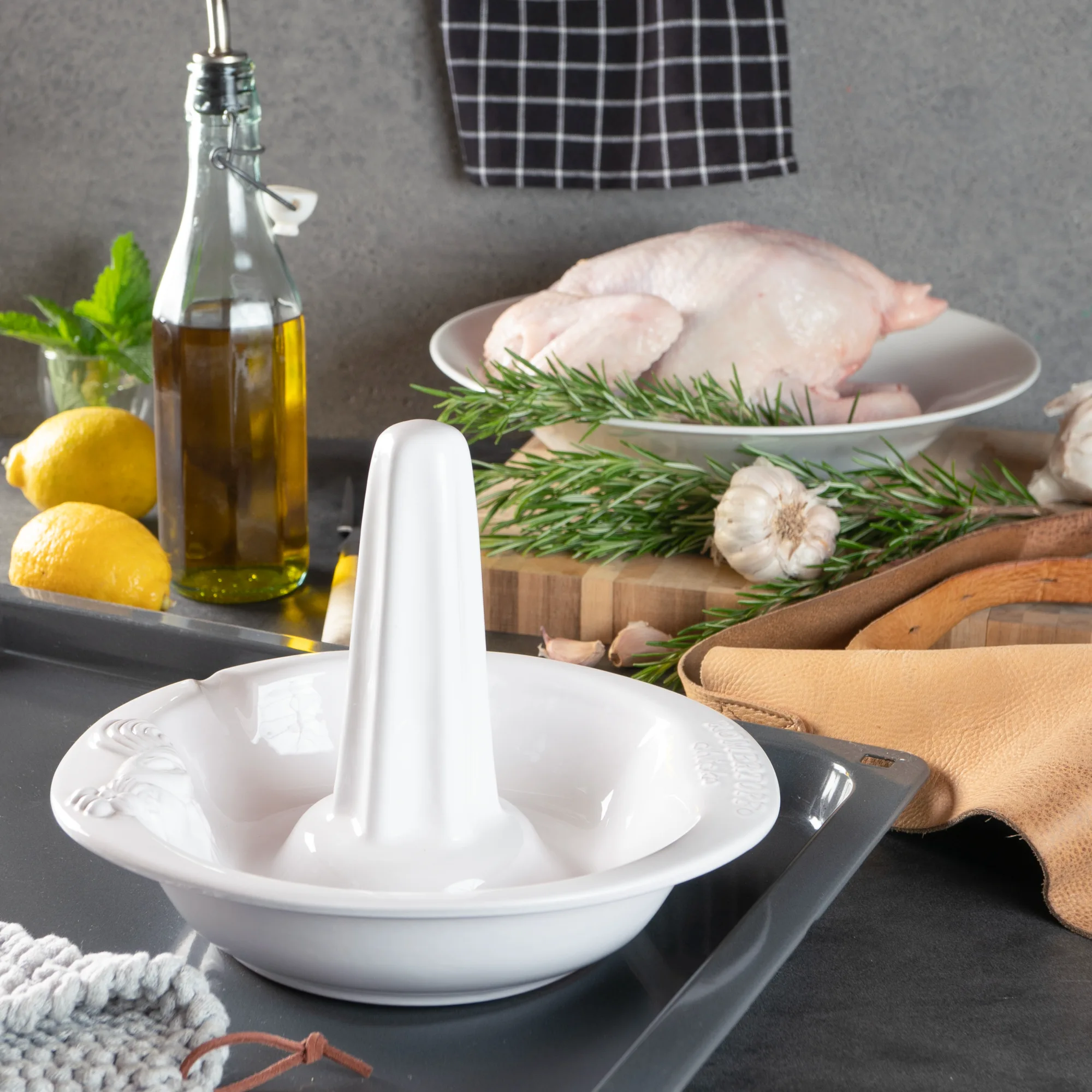 Römertopf Hähnchenbräter aus Ton mit Deckel – Gesundes Garen im Backofen Römertopf-Hähnchenbräter aus Keramik in heller Naturfarbe, bestehend aus einer rechteckigen Schale mit erhöhtem Mittelstab zum Aufstecken eines ganzen Hähnchens; dargestellt auf weißem Hintergrund.