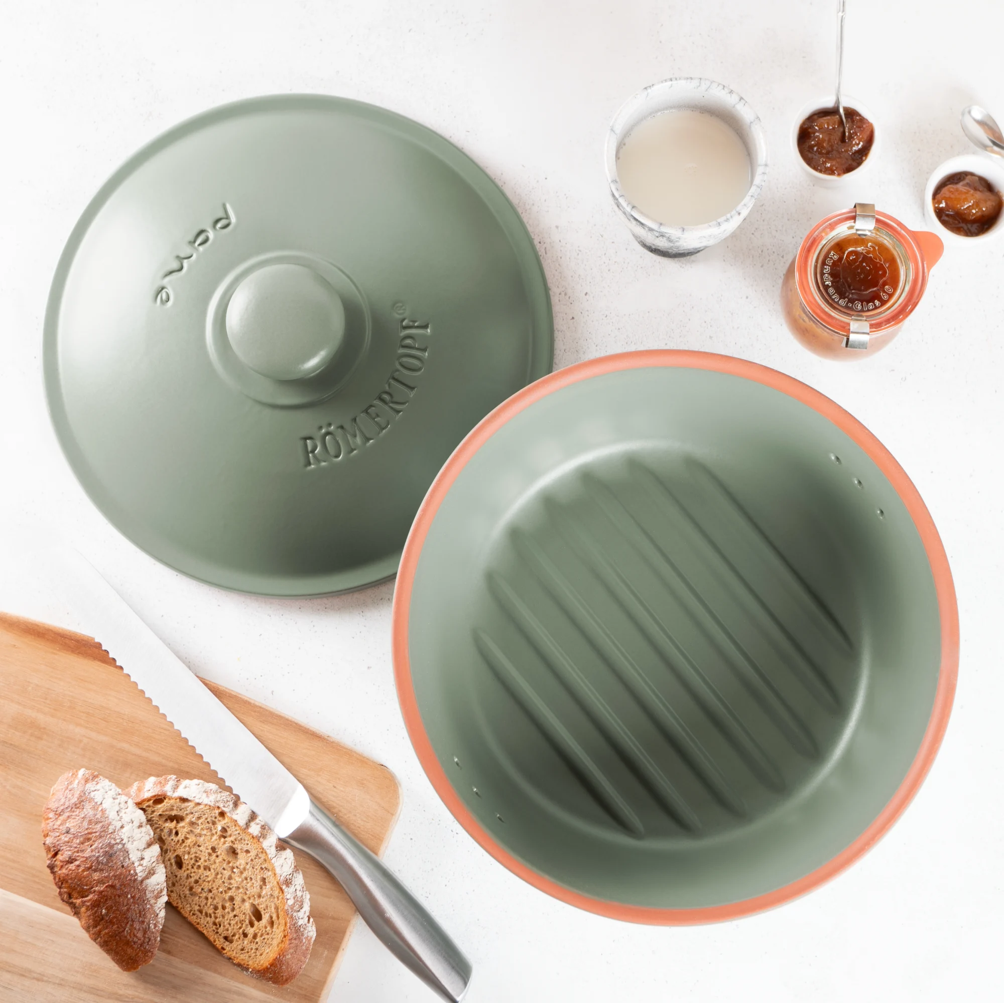 Römertopf Brottopf rund grün – Frischetopf zur Brotaufbewahrung aus Naturton Römertopf Brottopf in runder Form mit grün glasierter Oberseite und naturbelassener Unterseite, Deckel mit Lüftungslöchern für optimale Brotaufbewahrung, auf weißem Hintergrund.