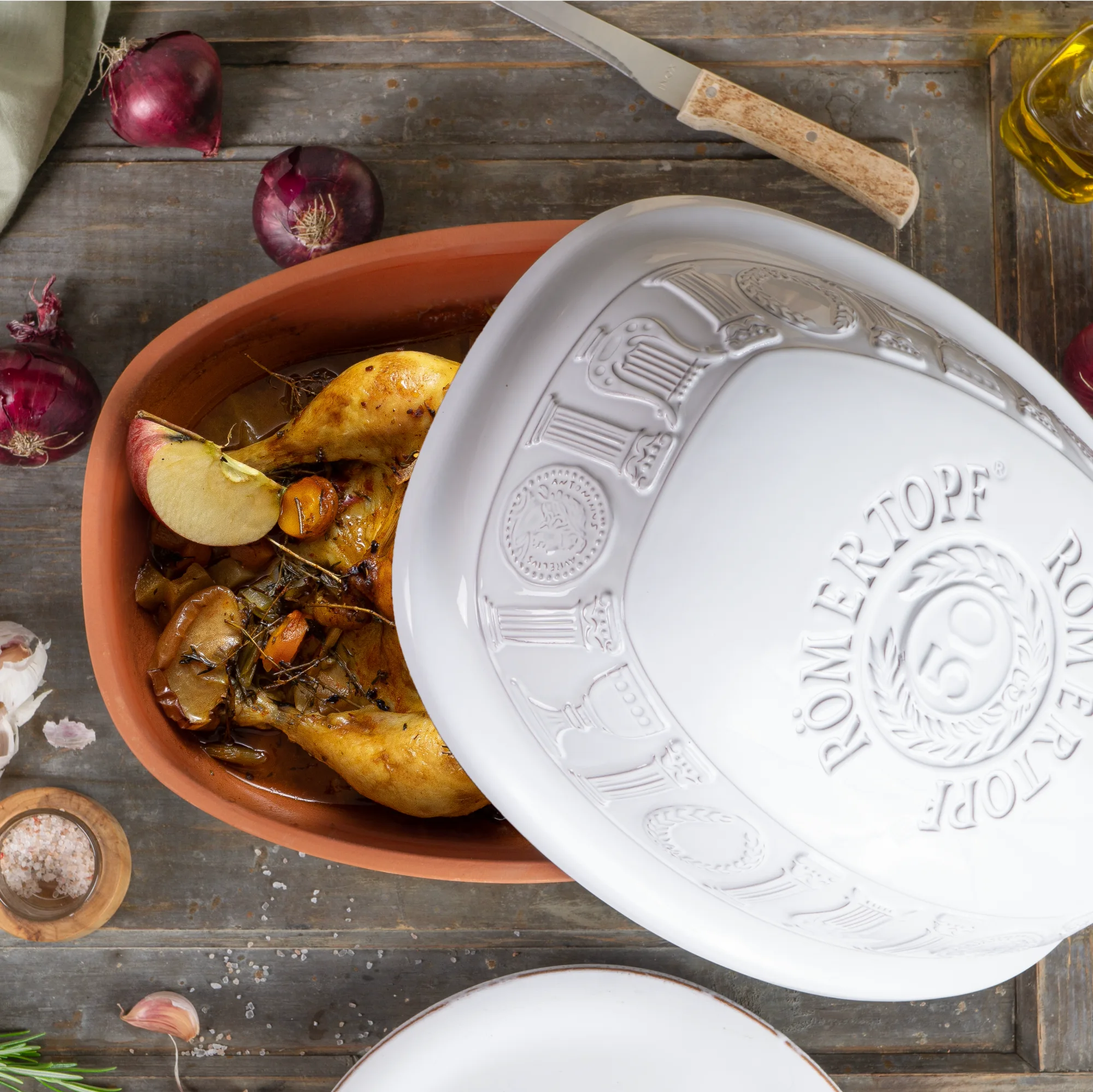 Römertopf Jubiläums-Bräter 50 Jahre – Weißer Keramikbräter mit Deckel Rechteckiger Römertopf-Bräter in cremeweiß mit Deckel, aus Ton gefertigt, Vorderseite mit geprägtem Schriftzug „50 Jahre“ und Reliefmotiv, auf weißem Hintergrund.