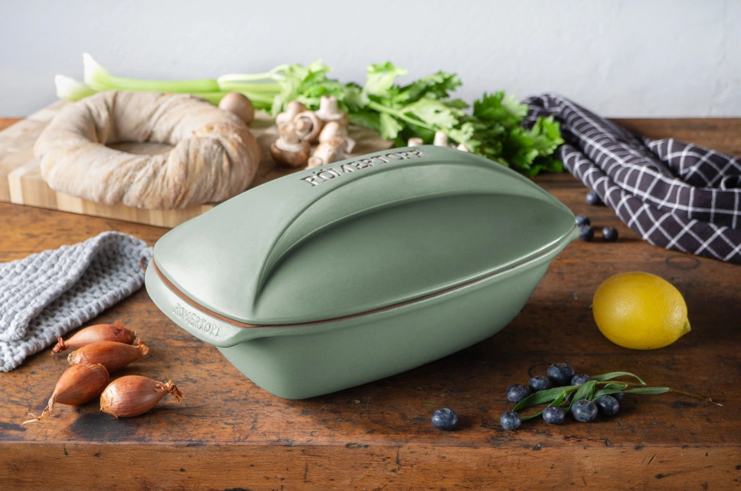 Römertopf Bräter aus Naturton – Ovaler Tontopf mit Deckel für fettfreies Garen Rechteckiger rötlich-brauner Römertopf-Bräter mit passendem Deckel aus Ton, auf hellem Untergrund stehend.