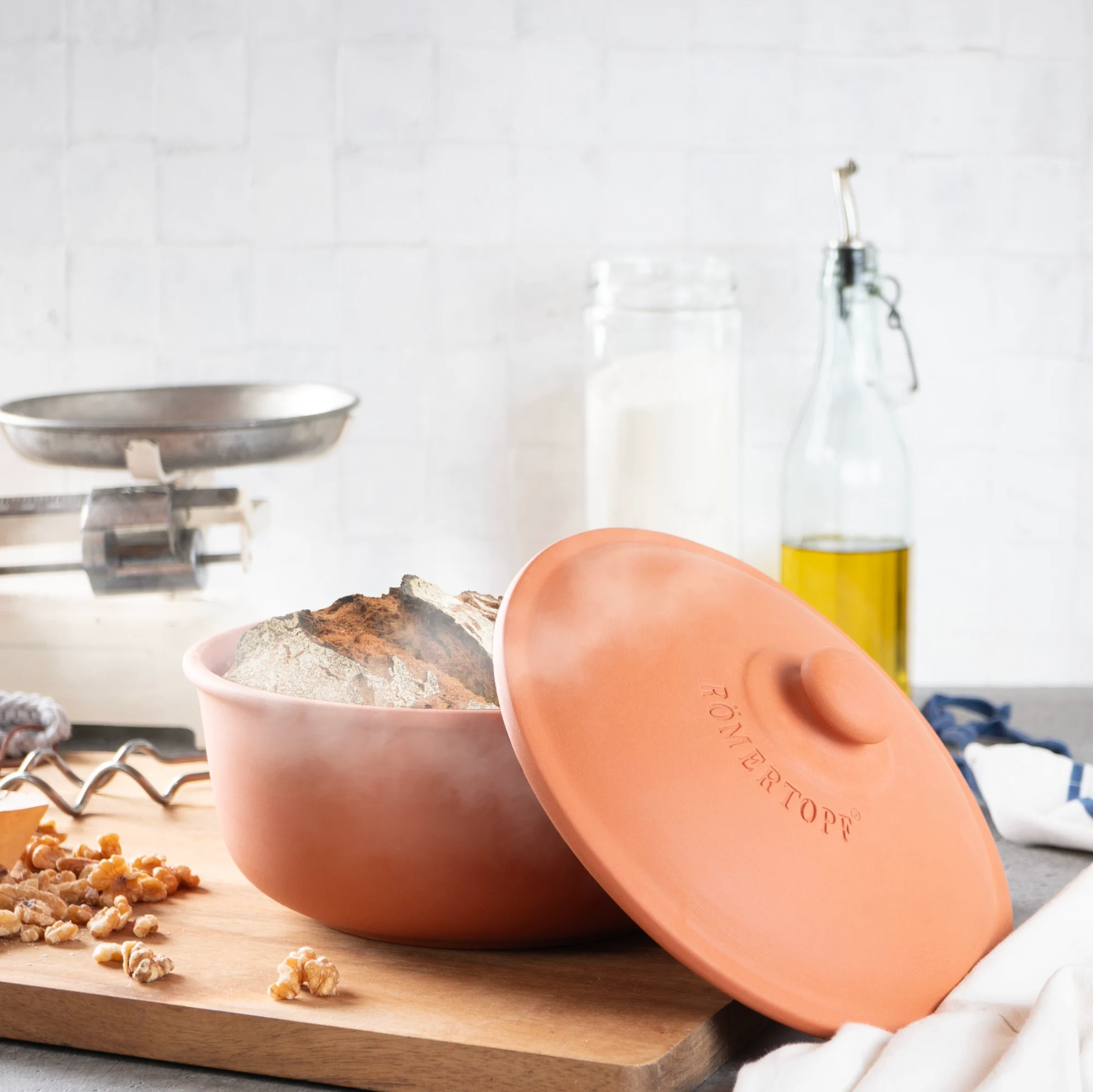 Römertopf Brotbacktopf aus Terracotta – ovaler Tontopf zum Brotbacken Römertopf Brotbacktopf aus Terrakotta mit Deckel, oval geformt, auf weißem Hintergrund stehend.
