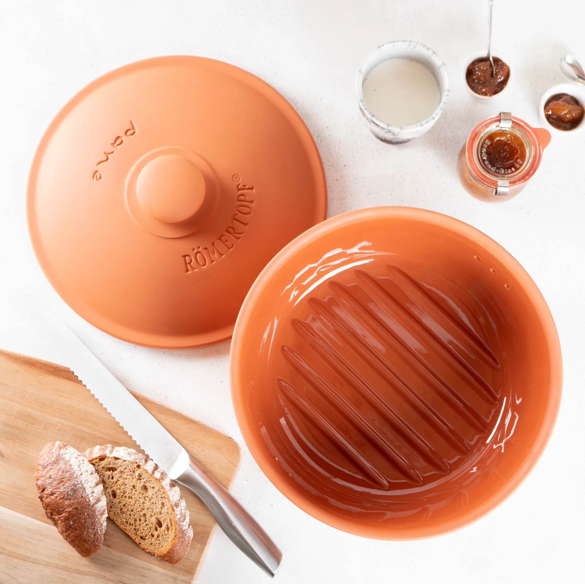 Römertopf Brottopf rund aus Natur-Terracotta zur Brotaufbewahrung – Atmungsaktiv für langanhaltende Frische Runder Römertopf Brottopf aus Terrakotta mit natürlicher, brauner Oberfläche und eingeprägtem "RÖMERTOPF"-Schriftzug auf dem Deckel, stehend auf weißem Hintergrund.