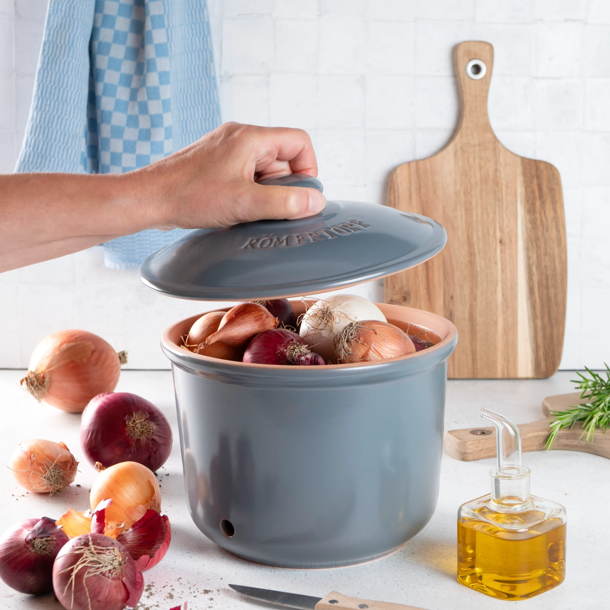 Römertopf Zwiebeltopf Maxi in Blaugrau – Frischetopf zur aromatischen Aufbewahrung von Zwiebeln Römertopf Zwiebeltopf aus Keramik in Blaugrau, mit gelochtem Deckel und seitlichen Griffmulden, stehend auf heller Oberfläche – zur luftdurchlässigen Aufbewahrung von Zwiebeln.