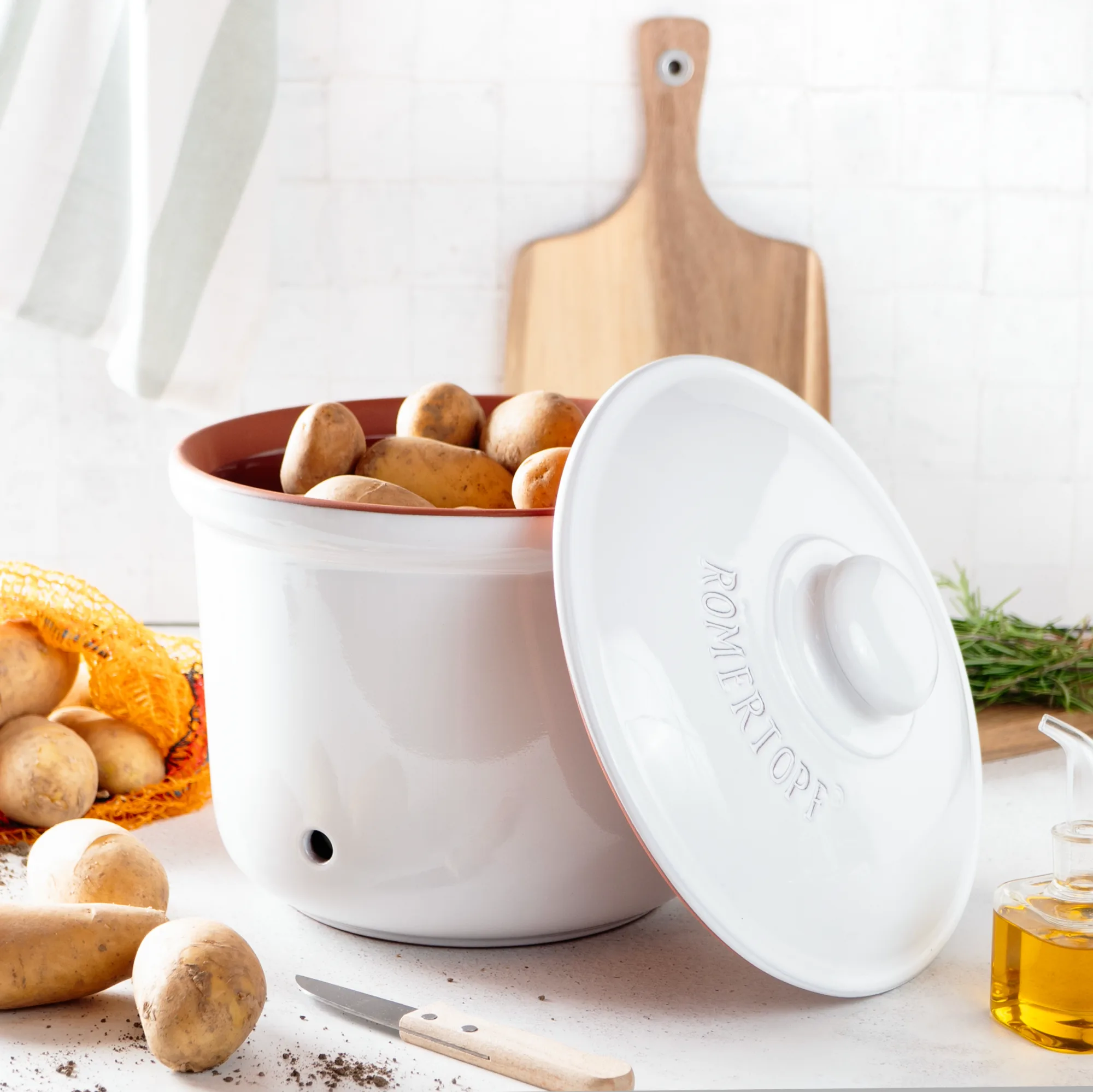 Römertopf Vorratstopf Set aus Keramik in Weiß – luftdicht & atmungsaktiv zur Aufbewahrung von Lebensmitteln Set aus drei weißen Römertopf-Vorratstöpfen mit Deckel in unterschiedlichen Größen, aus Keramik mit atmungsaktiver Glasur, jeweils mit Beschriftung für Zwiebeln, Knoblauch und Kartoffeln, vor neutralem Hintergrund.