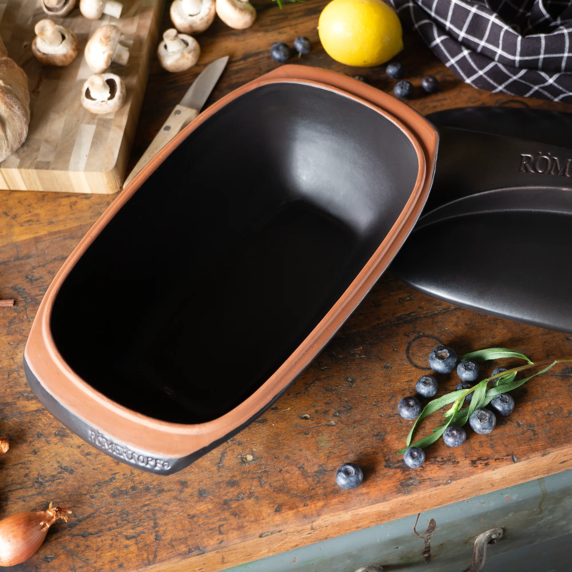 Römertopf Bräter Culinario Schwarz – Ovaler Tontopf mit Deckel für schonendes Garen Schwarzer Römertopf-Bräter der Serie Culinario mit Deckel, aus Keramik, auf weißem Hintergrund.