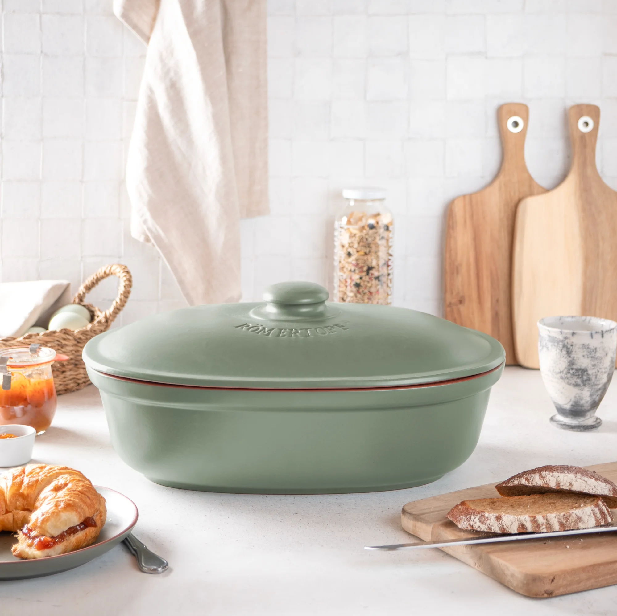 Frischetopf Maxi Grün aus Keramik zur Brotaufbewahrung – Römertopf® Aufbewahrungsdose Grüner Römertopf Brot-Frische-Topf Maxi mit Deckel, seitlich geöffnet, auf hellem Untergrund; Innenraum glatt, Außenseite mit Rillenstruktur und Römertopf-Logo.