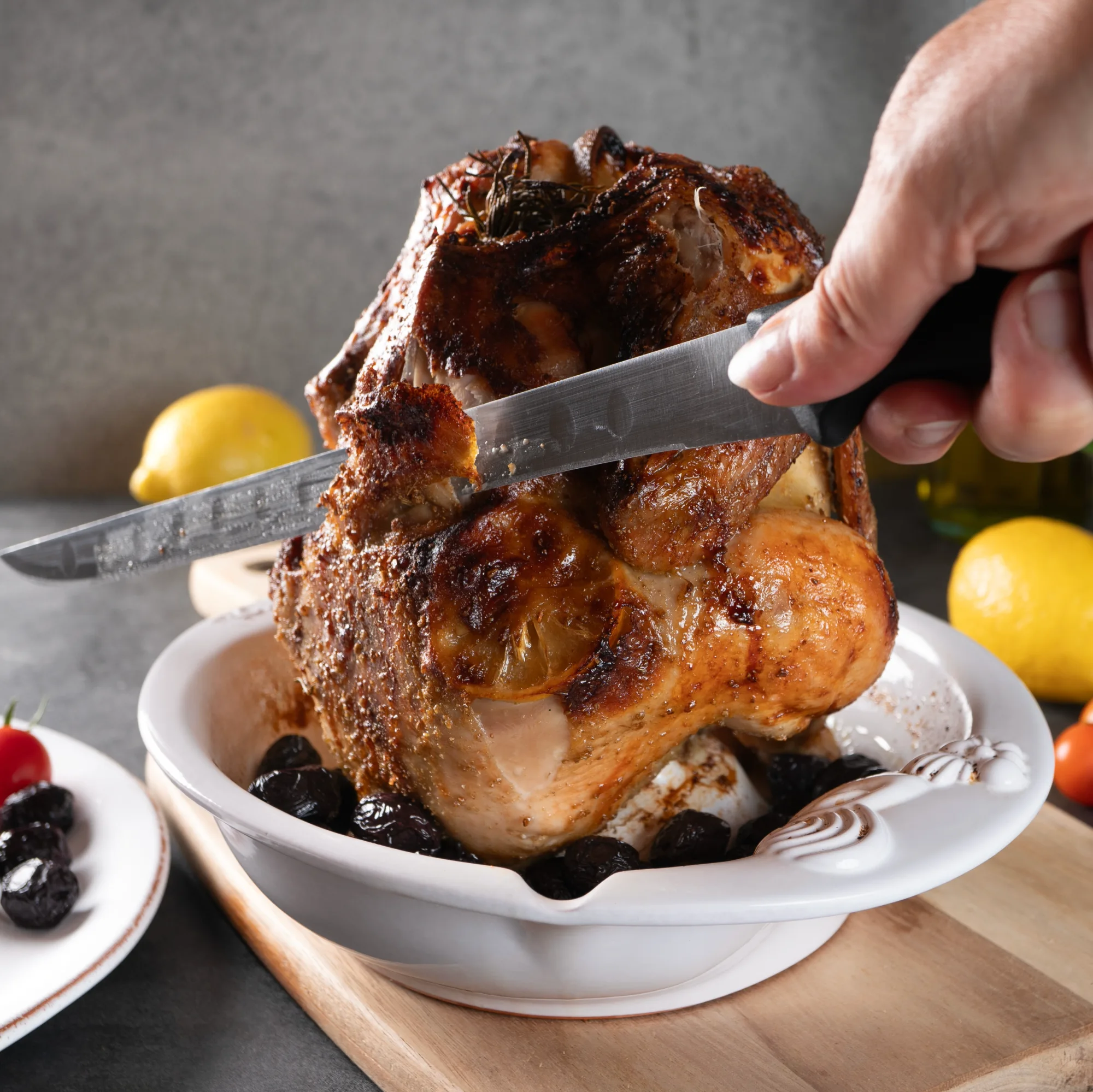 Römertopf Hähnchenbräter aus Keramik mit Grill-Einsatz für knuspriges Geflügel Römertopf Hähnchenbräter aus Keramik in Braun, bestehend aus einem rundlichen Unterteil mit Mittelspieß zum Aufsetzen des Hähnchens und einem flachen Ringrand für Gemüse oder Beilagen; Produkt auf weißem Hintergrund fotografiert.