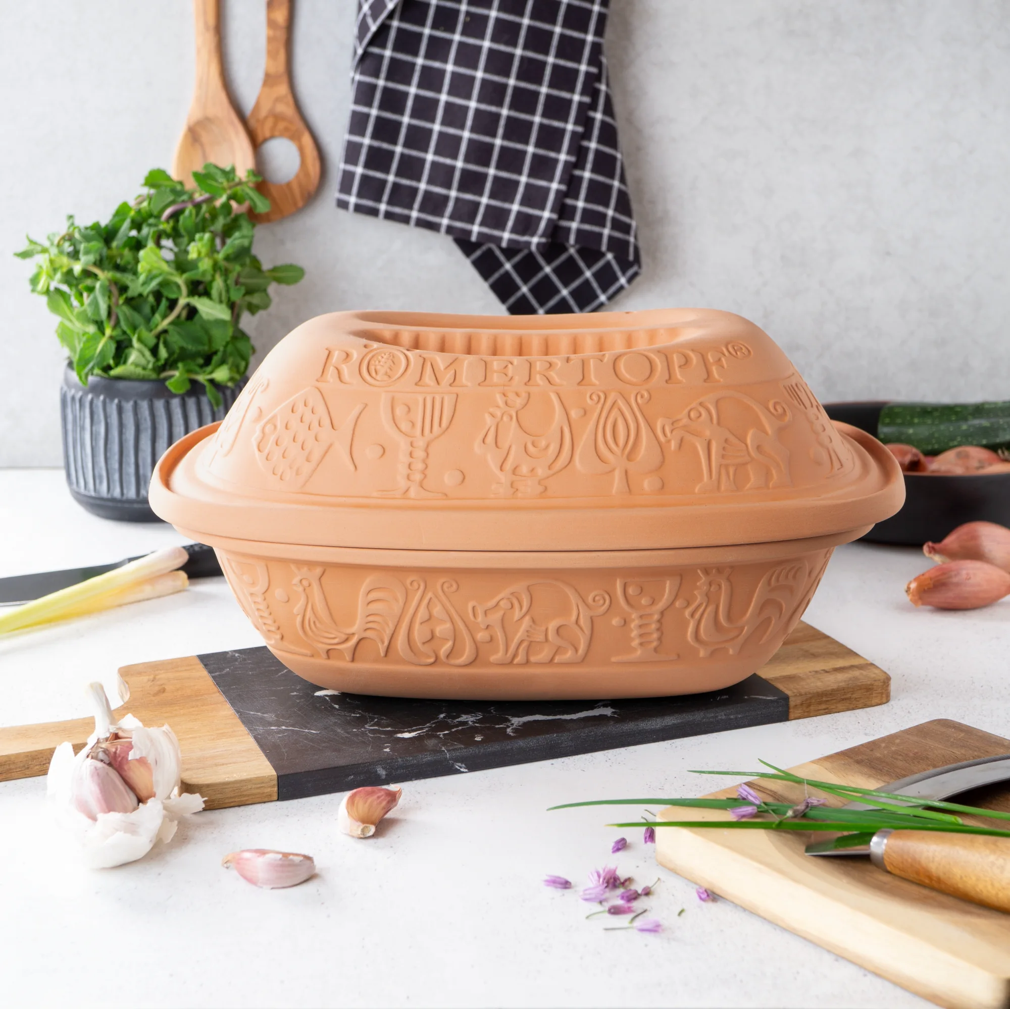 Klassischer Römertopf Bräter aus Naturton mit Deckel – ideal zum fettarmen Garen Klassischer Römertopf-Bräter aus naturbelassenem Ton mit Deckel, oval geformt, auf weißem Hintergrund – geeignet zur fettarmen Zubereitung von Speisen im Backofen.
