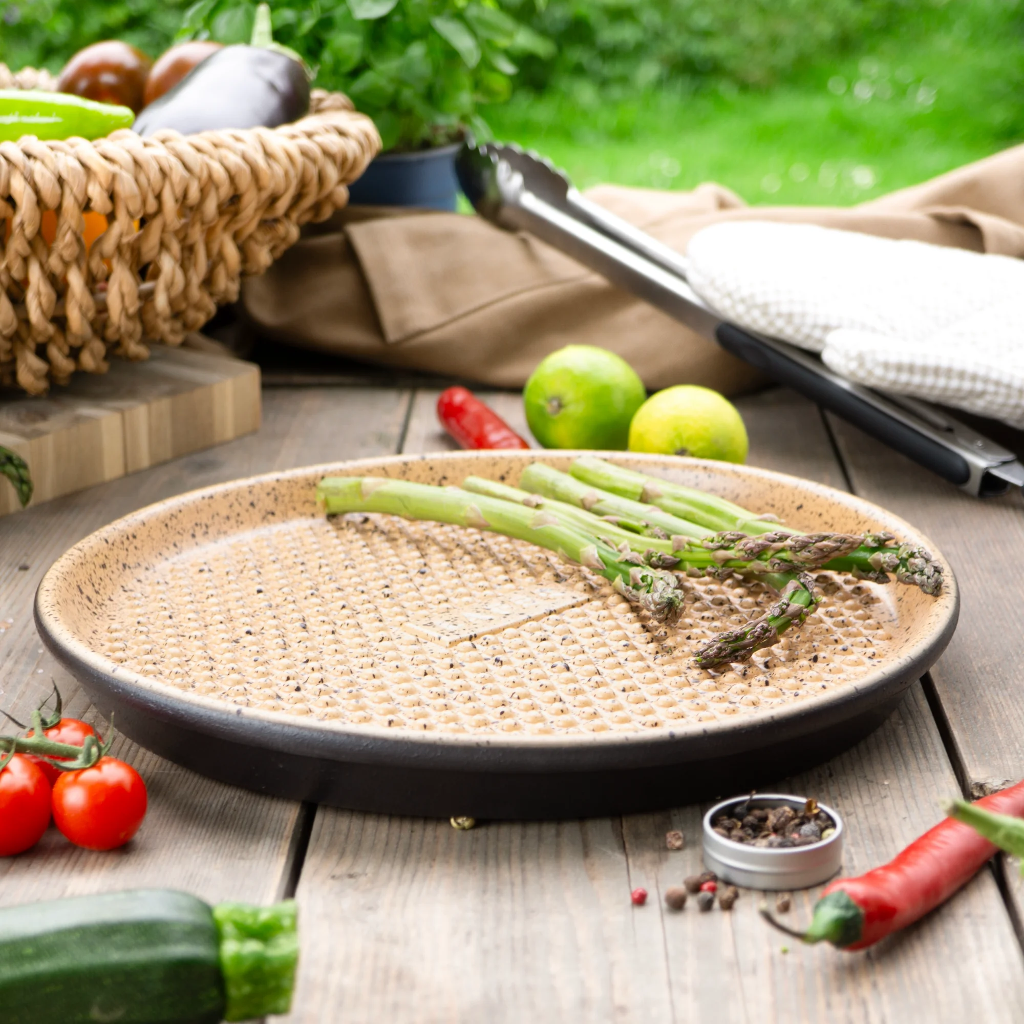 Römertopf Plancha rund mit Noppen – Grillplatte aus Naturton für gesundes Braten Runde rötlich-braune Römer-Topf Plancha aus Ton mit erhobenen Noppen auf der Oberfläche, liegt auf hellem Untergrund.