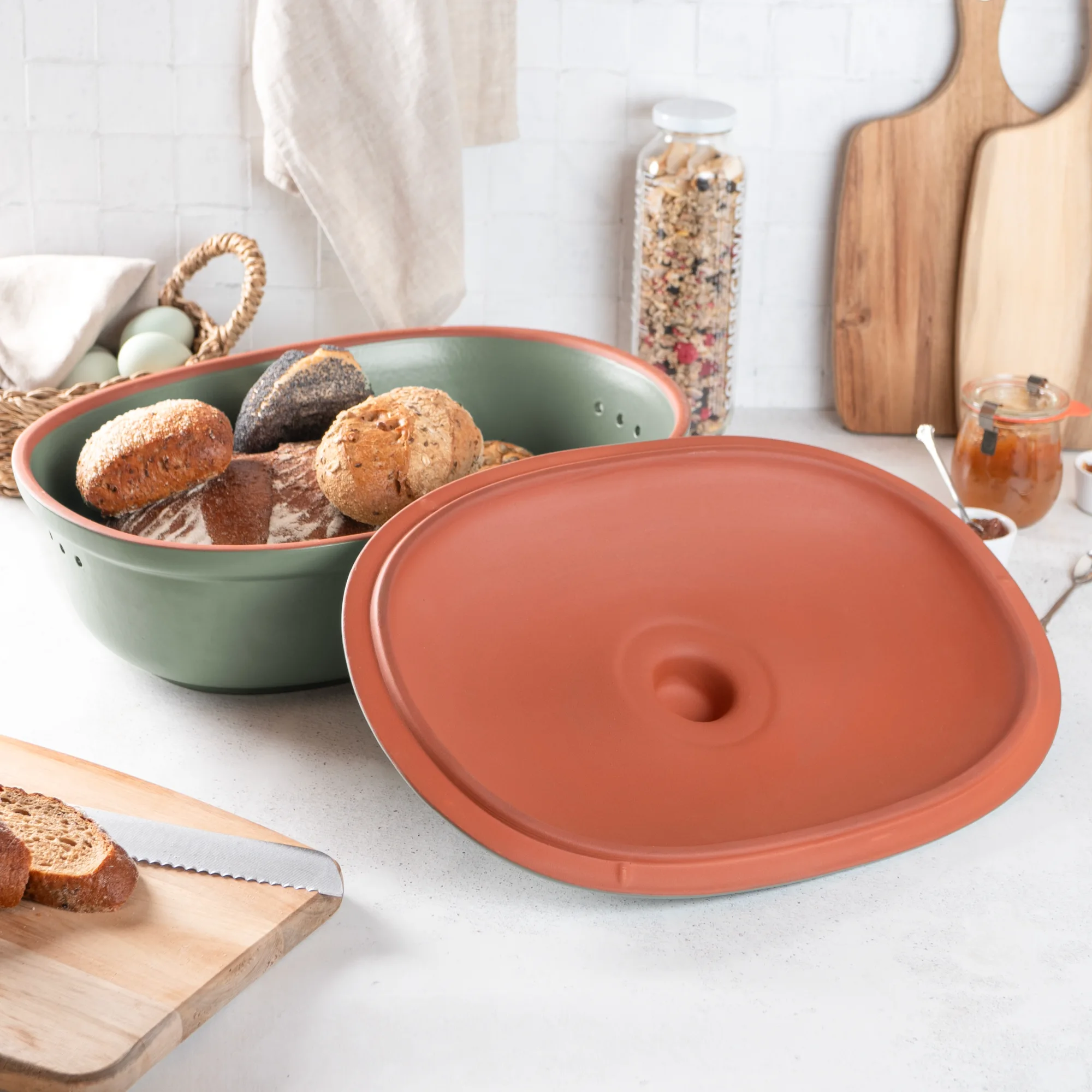 Römertopf Brottopf Maxi Grün – Frischebehälter für Brot und Brötchen Grüner Römertopf Brot-Frischetopf Maxi mit Deckel, auf einem Holztisch stehend; im Inneren liegt ein rundes Laib Brot, weitere Brotscheiben daneben.