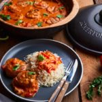 Ein Teller mit Reis und Paprika in Tomatensauce, präsentiert neben einem Römertopf voller derselben Speise.