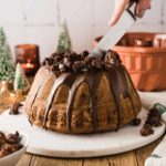 Person schneidet Schokoladenkuchen auf Marmorplatte an, dekoriert mit Krümeln, festliche Atmosphäre.