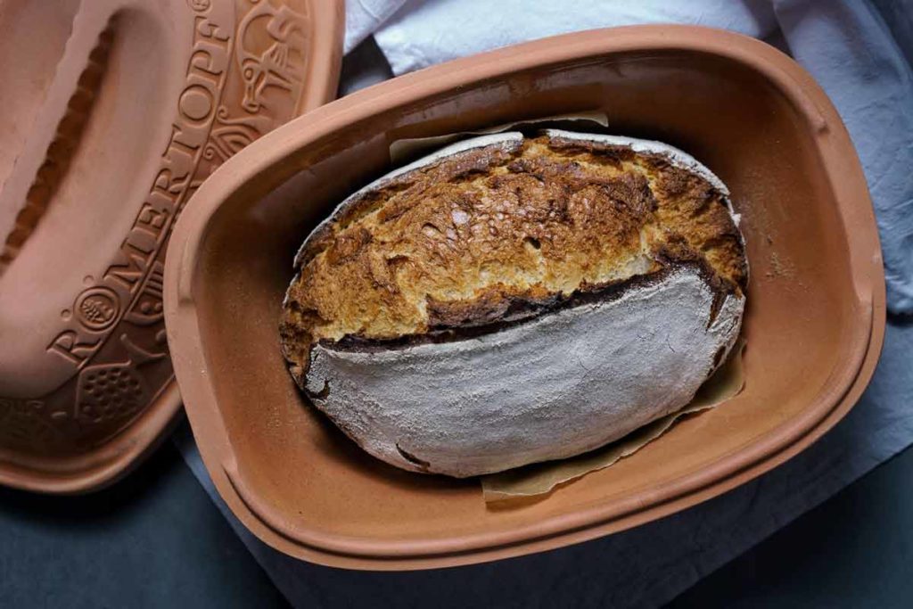 Frisch gebackenes Brot in einem Römertopf aus Ton, mit knuspriger, goldbrauner Kruste.