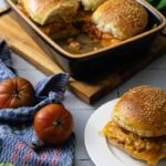 Frische Brötchen mit Käsefüllung in einer Schale, daneben Tomaten und ein einzelnes Brötchen auf einem Teller.