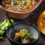 Schüssel mit herbstlichem Eintopf, gefüllt mit Gemüse und Fleisch, auf einem Holztisch serviert.