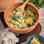 Ton-Topf mit Gnocchi, Spinat und Garnelen in cremiger Sauce, daneben eine Schüssel mit derselben Speise.