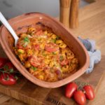 Gebratene Tortellini in Tomatensoße und Käse in einem Terrakotta-Behälter, dekoriert mit Petersilie.