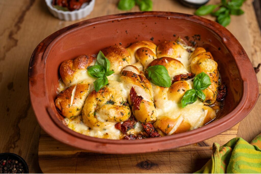 Laugen Grillbrot mit geschmolzenem Mozzarella, getrockneten Tomaten und frischem Basilikum im Römertopf Classico Bräter